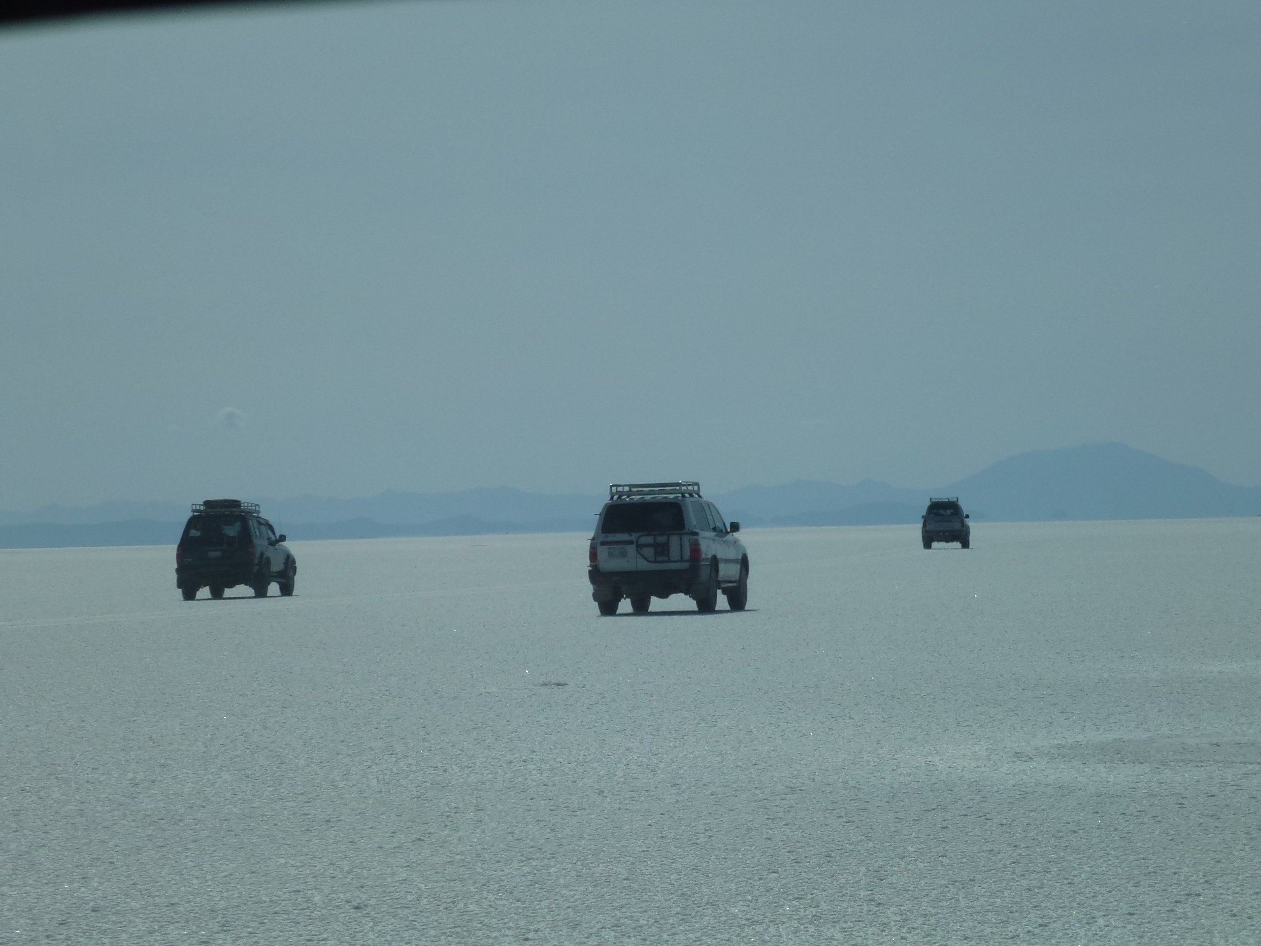 真っ白なウユニ塩湖の上を走る四駆の車