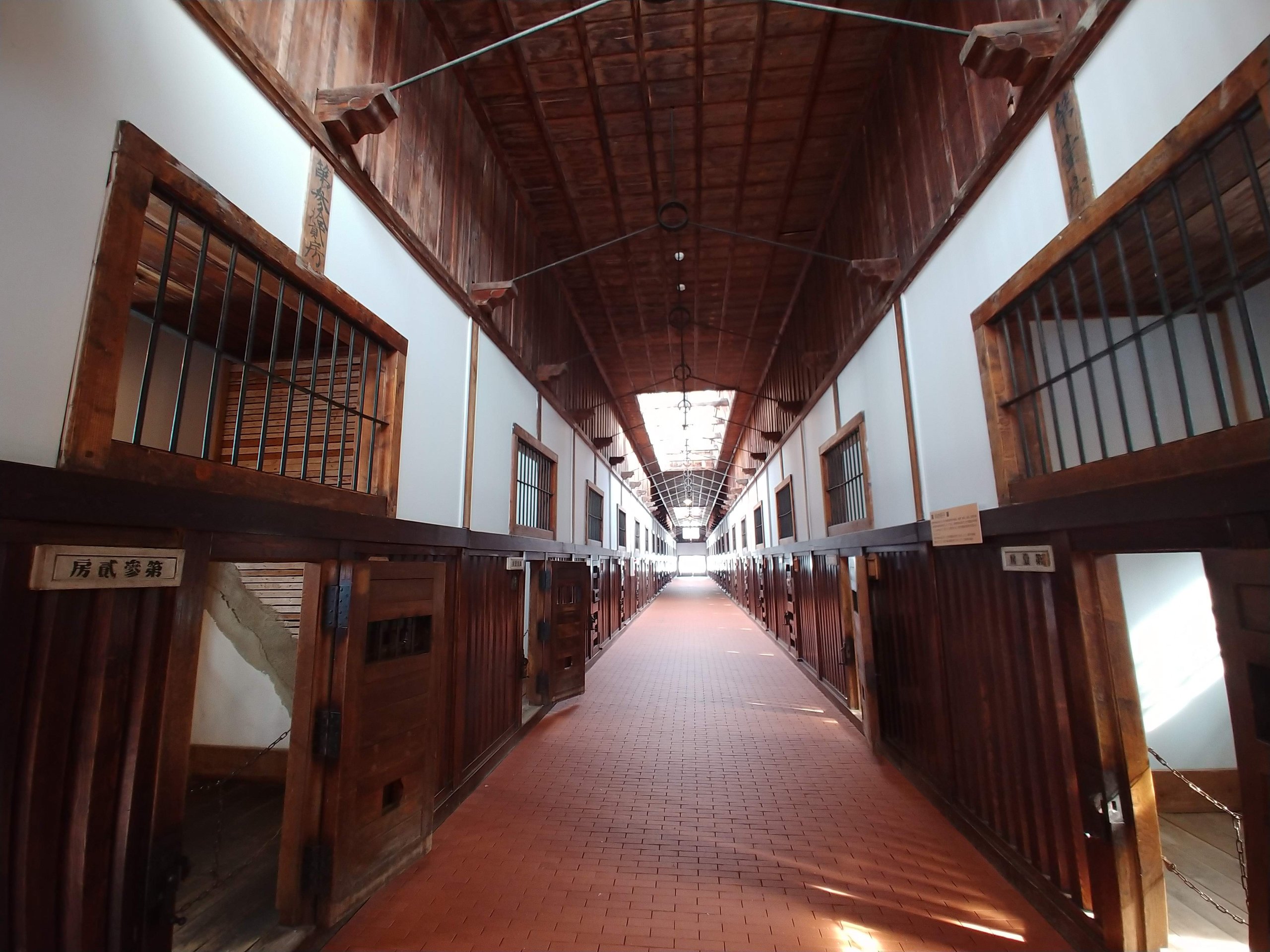 木の格子の部屋が両側に並ぶ舎房の長い廊下