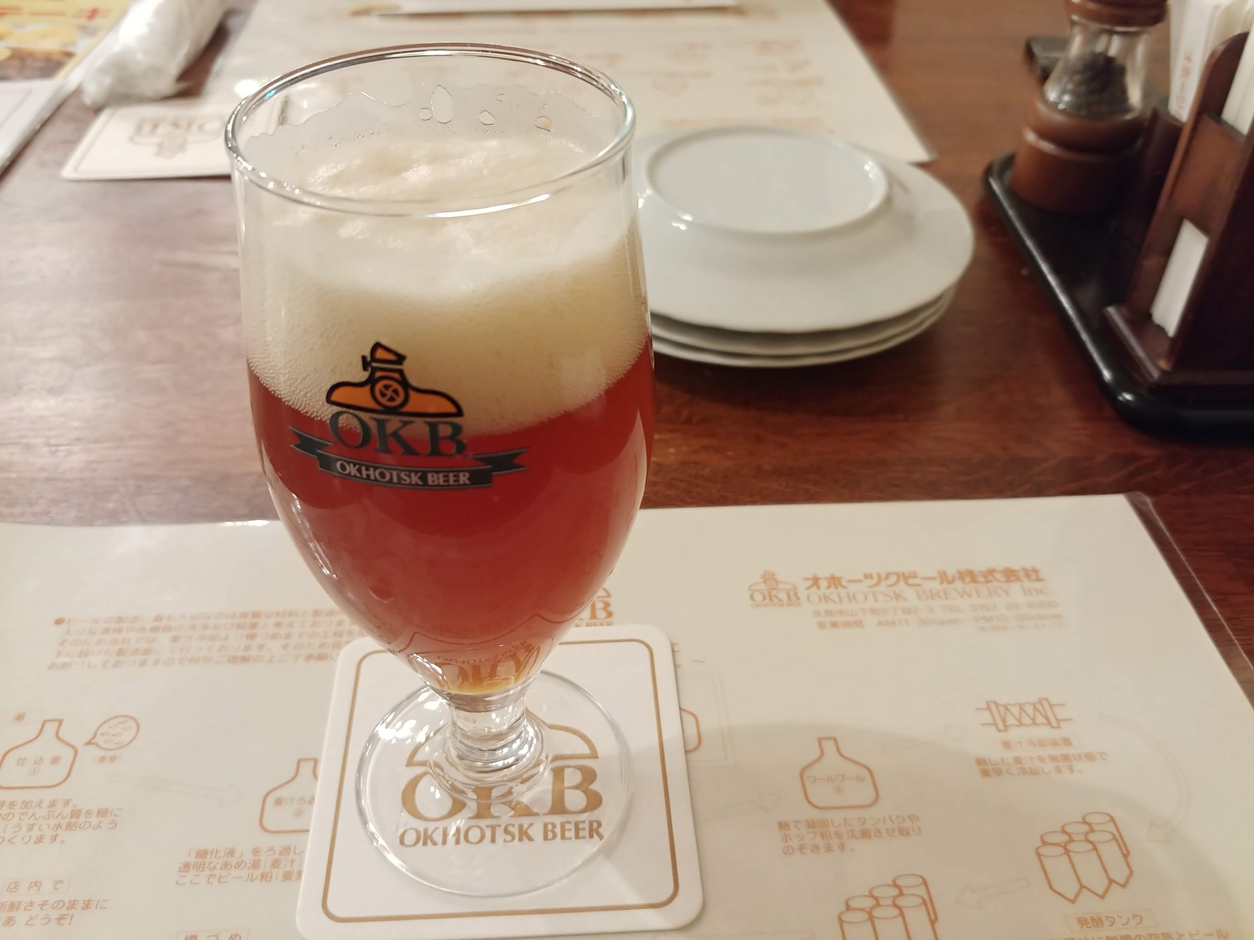 「OKHOTSK BEER」のロゴ入りグラスに注がれた赤いビール