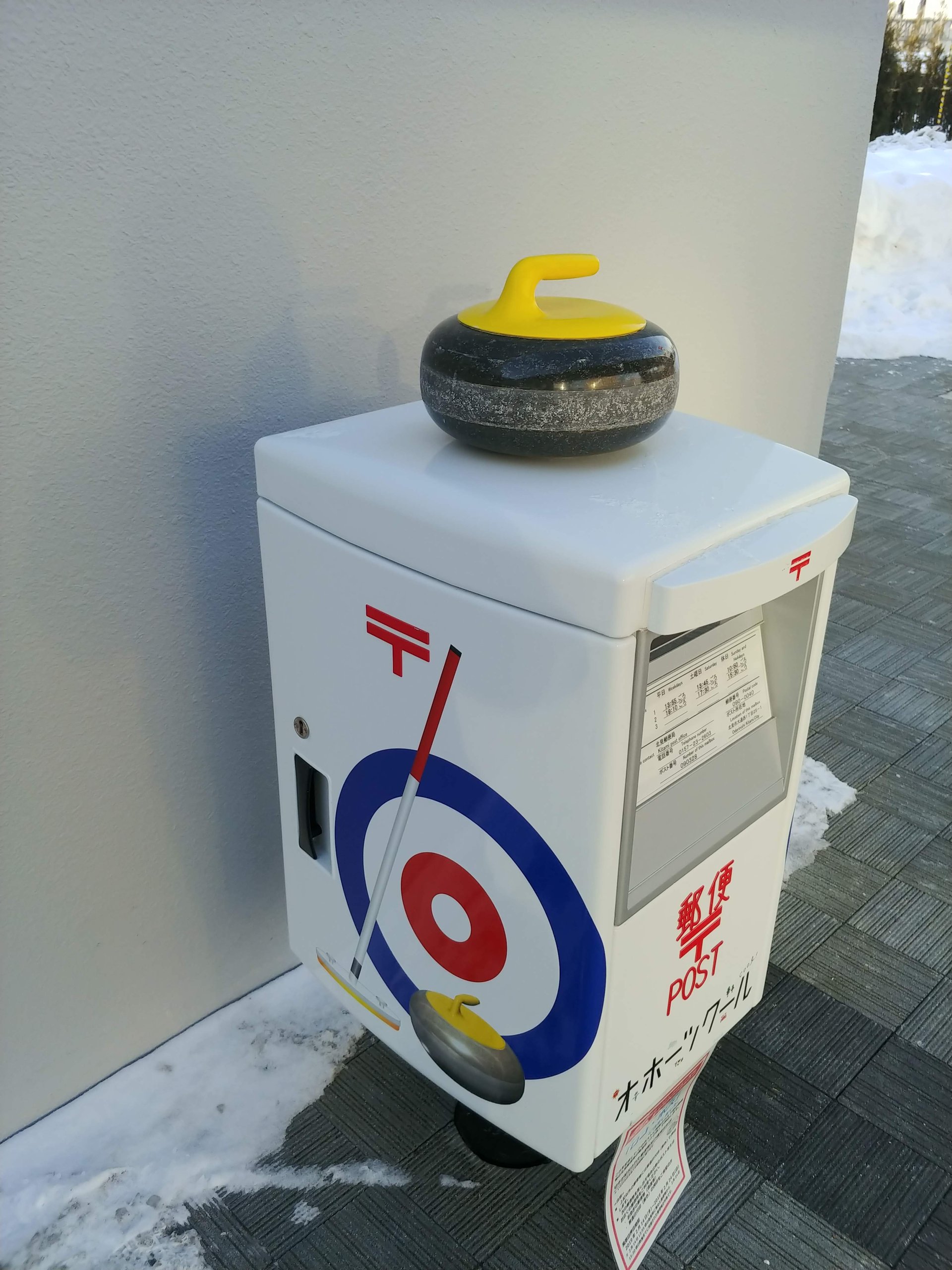 カーリングのストーンがのった白いポスト