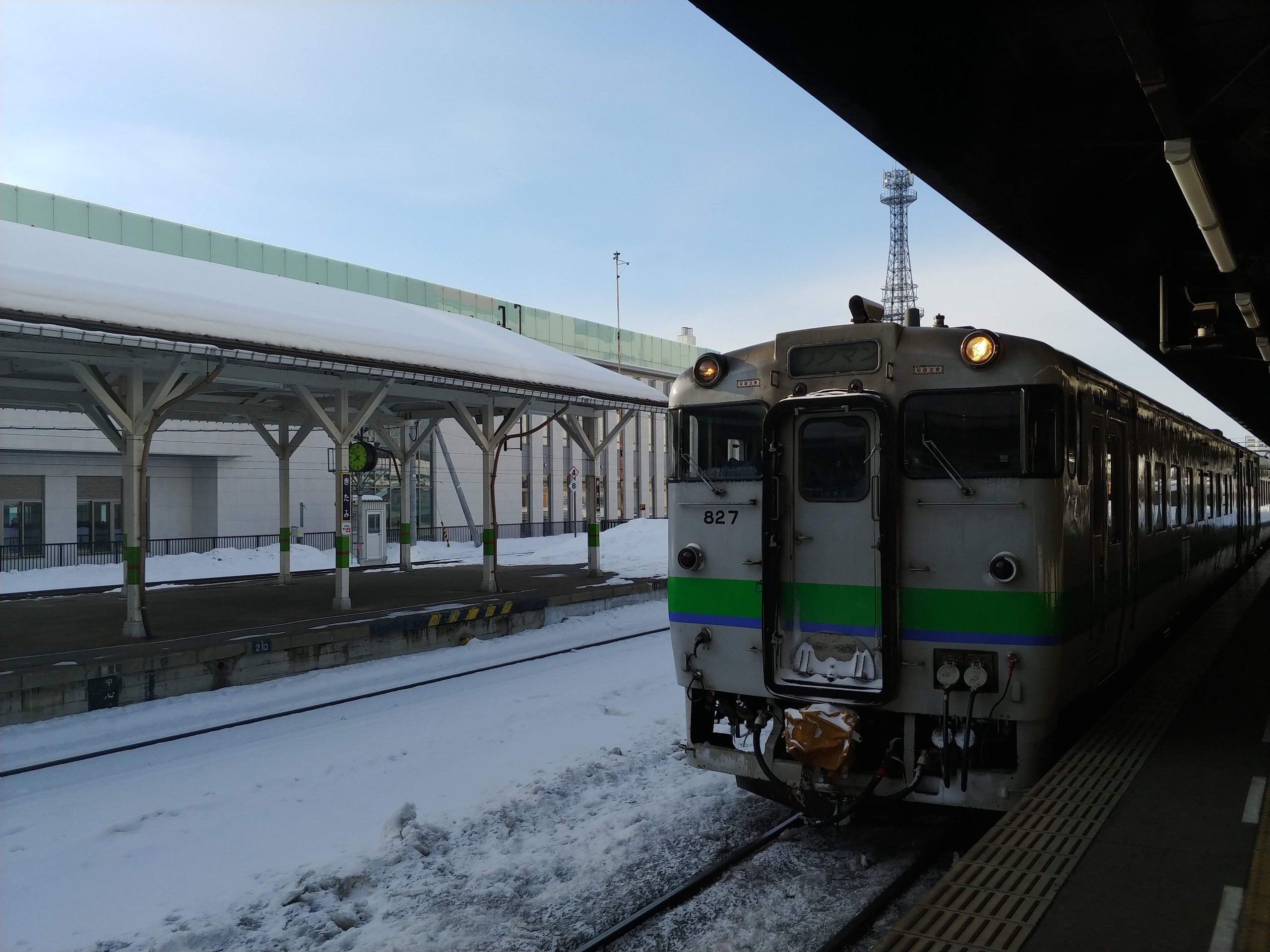 雪のホームに停まるJRのディーゼルカー