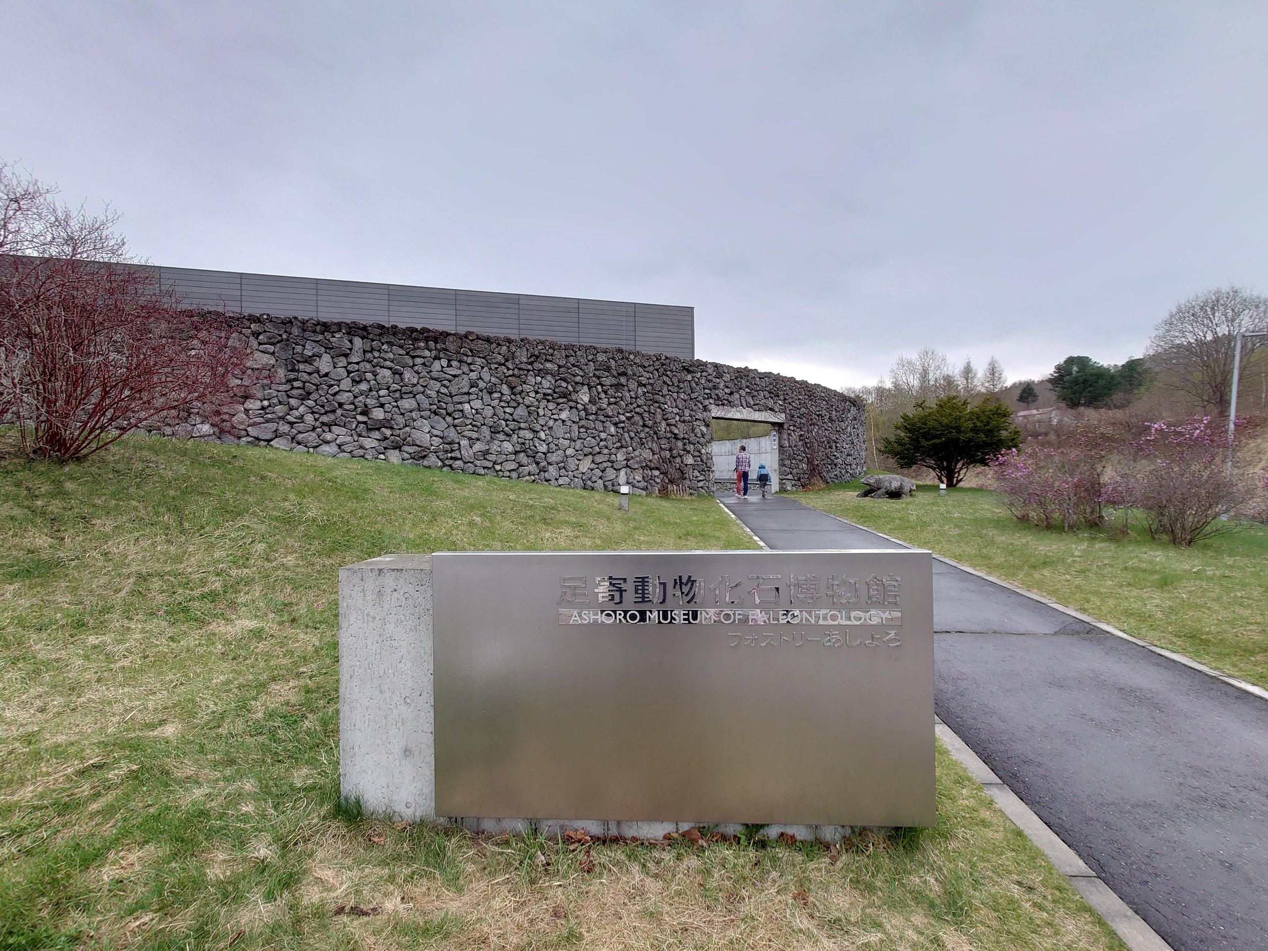 石積みの壁が続く足寄動物化石博物館の入口と館名の石碑