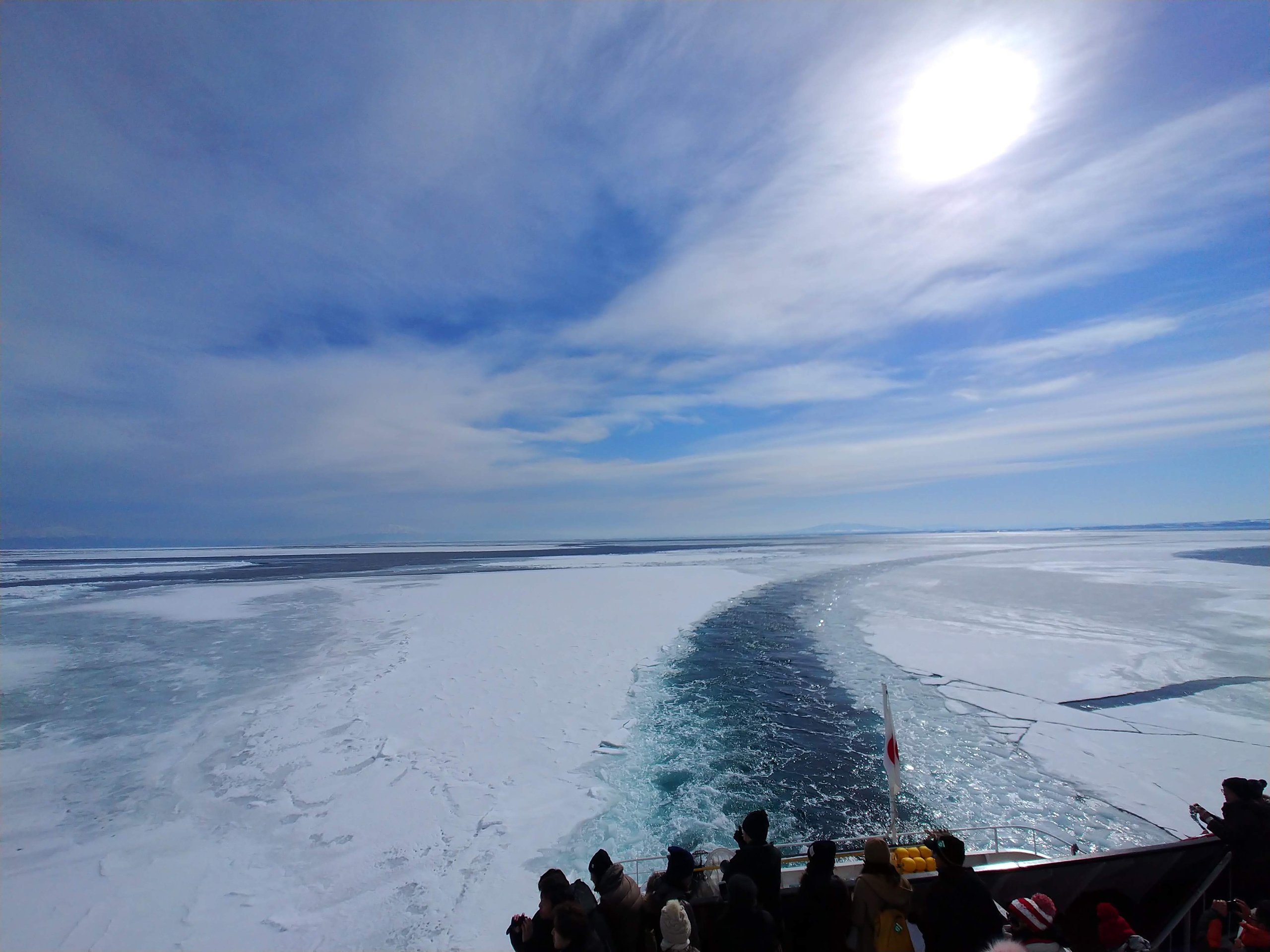 砕氷船が通ったあとに流氷が割れてできた海の道と、デッキの乗客の後ろ姿