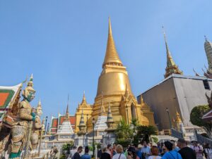 青空にそびえる金色の仏塔と、門を守る鬼の像