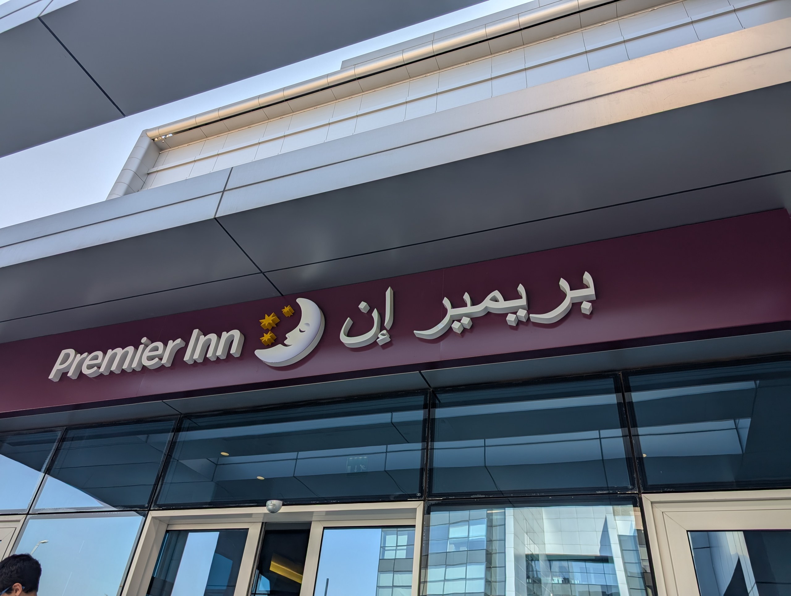 「Premier Inn」の英語とアラビア語の看板が付いたホテルの入口