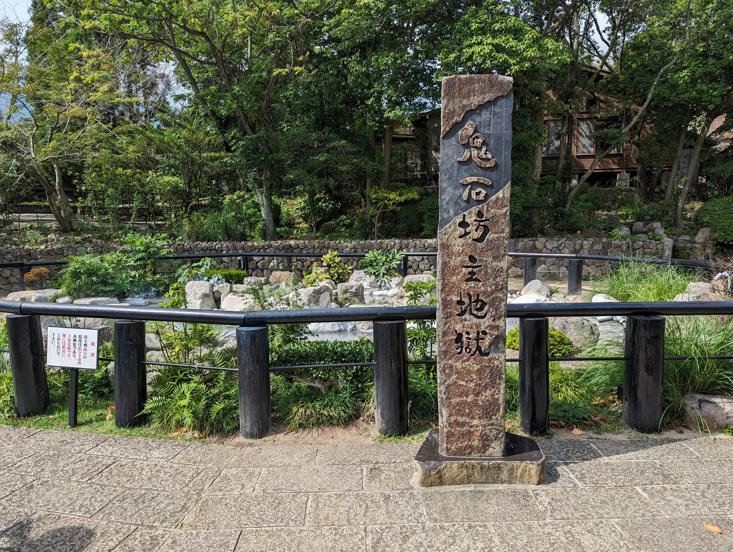 「鬼石坊主地獄」の石柱と、垣根に囲まれた庭
