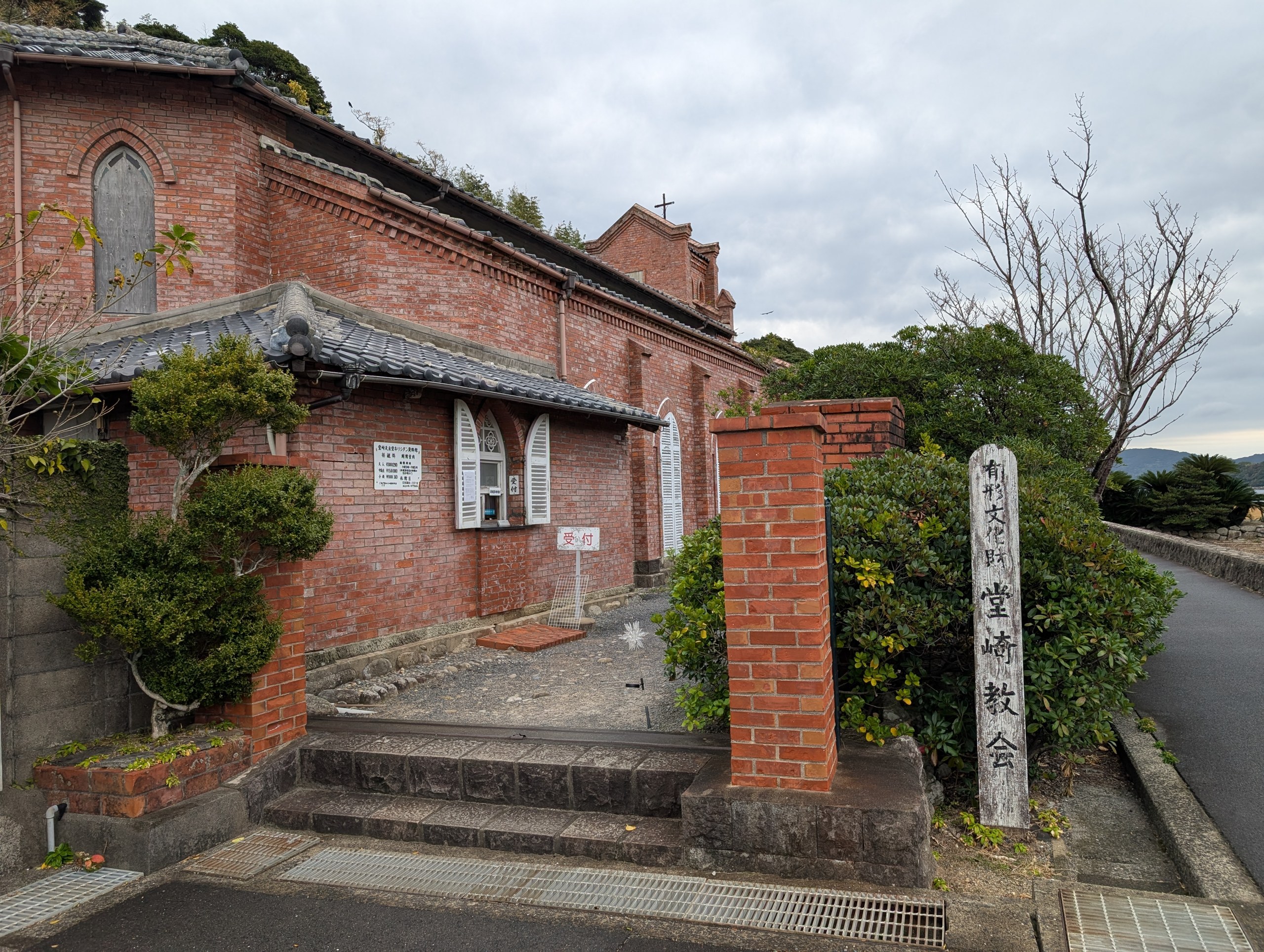 石の門柱と植え込みの先に見える、教会の横顔