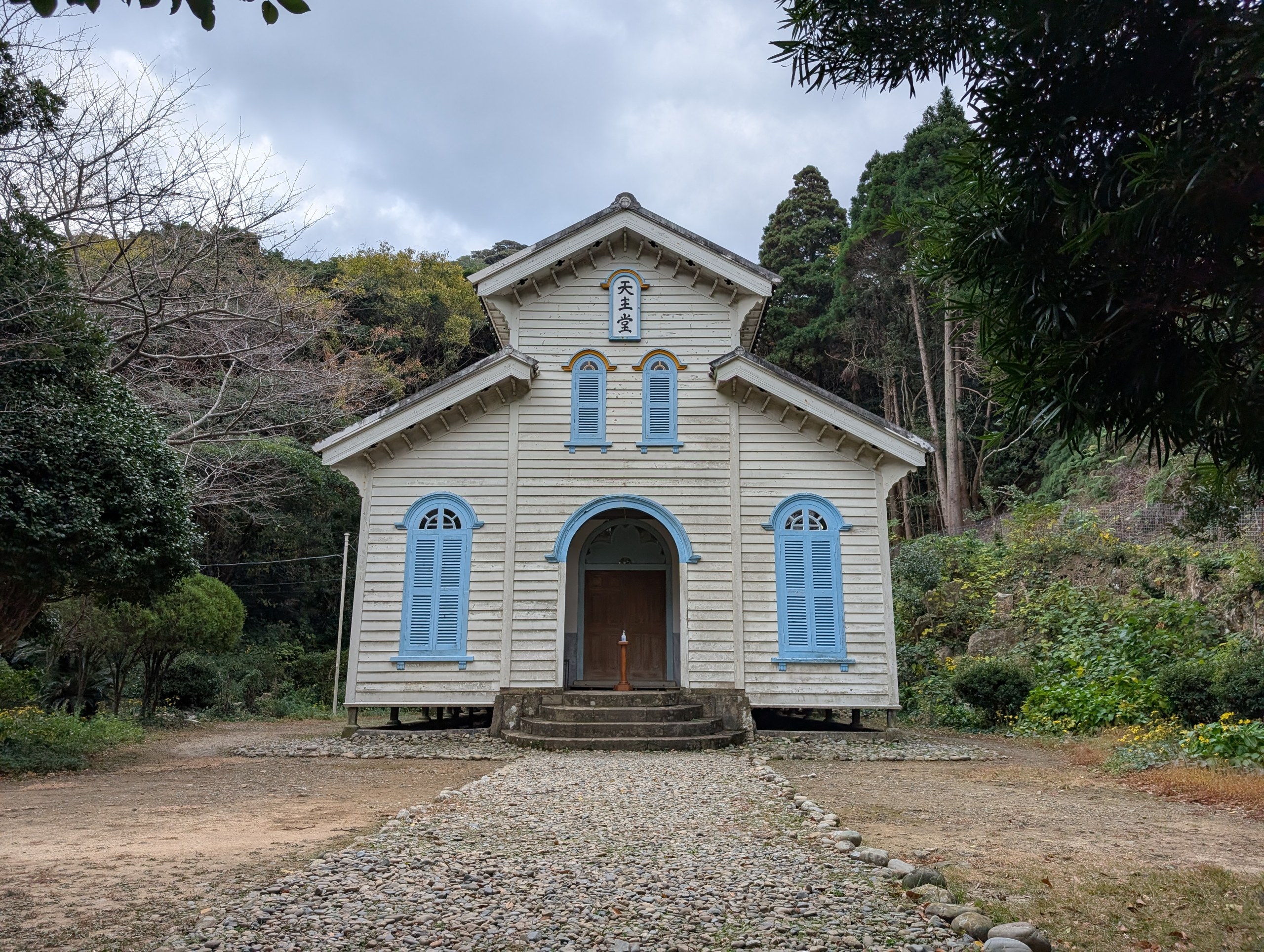 砂利の道の先に建つ、白い木造の江上天主堂