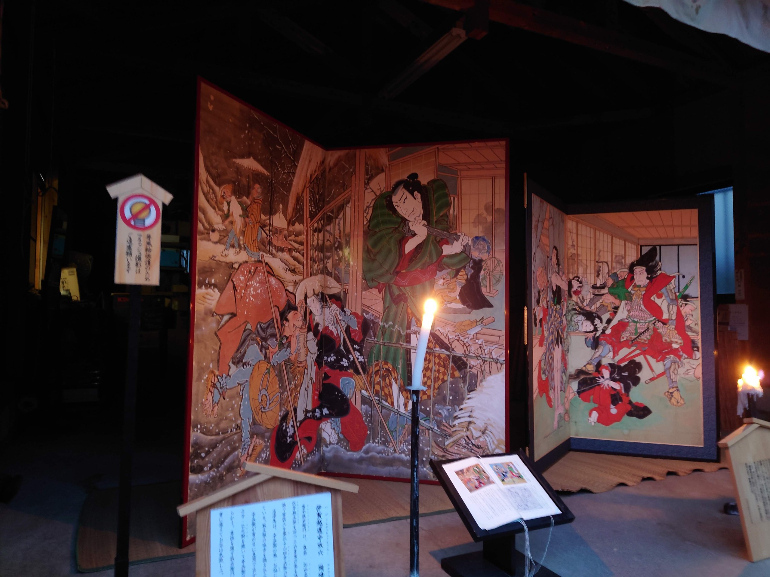 ろうそくに照らされる、二枚の芝居絵屏風