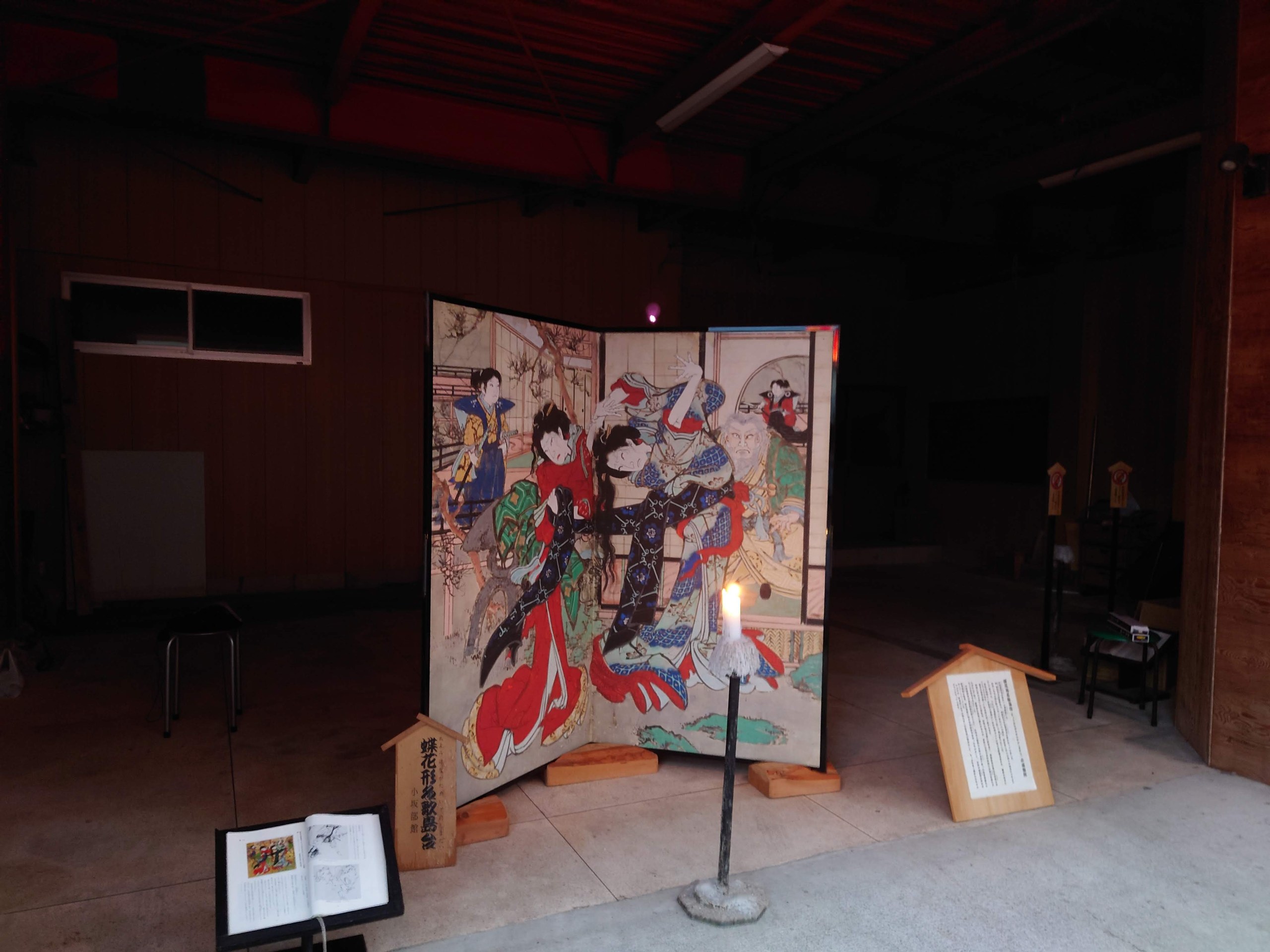 軒先に置かれた芝居絵屏風と、手前のろうそく
