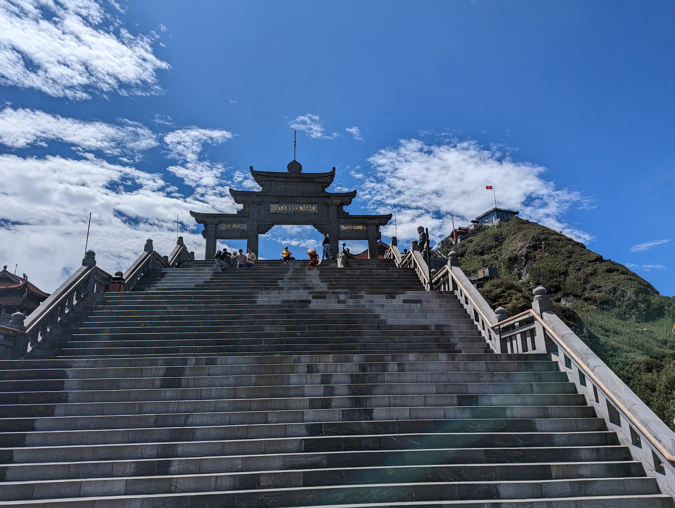 青空の下、山上に建つ門と長い石段