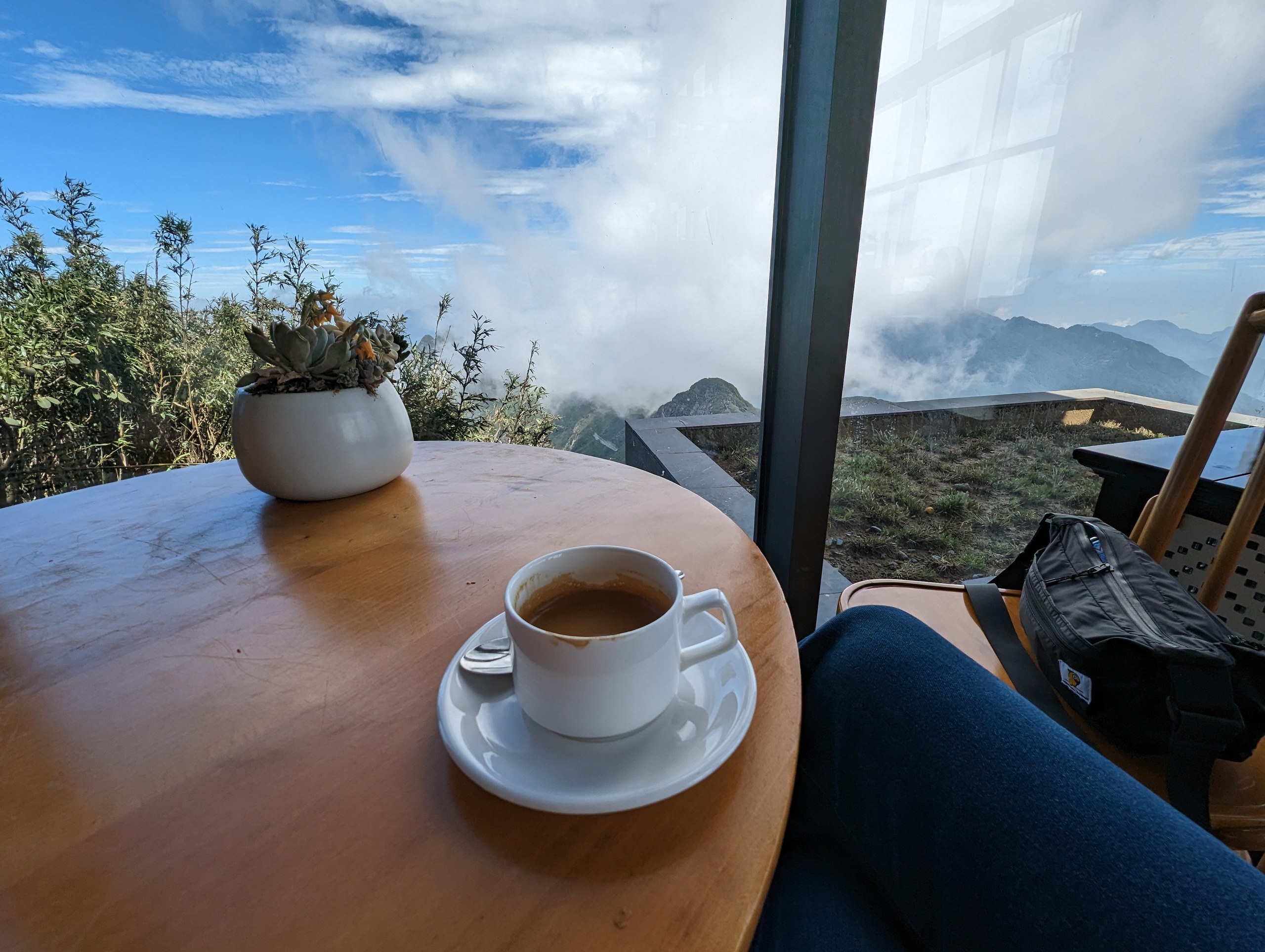 窓辺のテーブルのコーヒーと、雲に包まれた外の景色