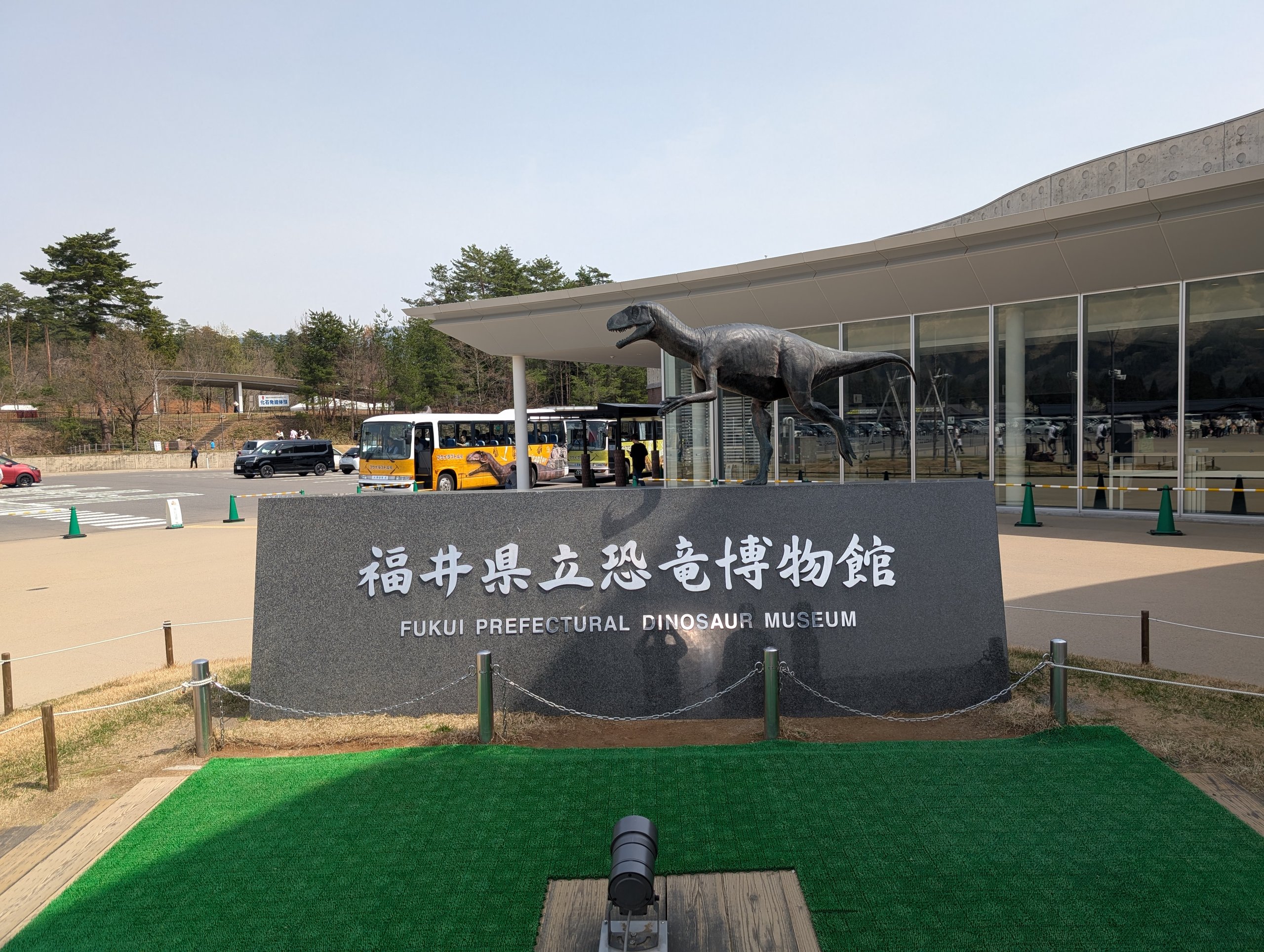 「福井県立恐竜博物館」と書かれた石と、建物の上の恐竜の像