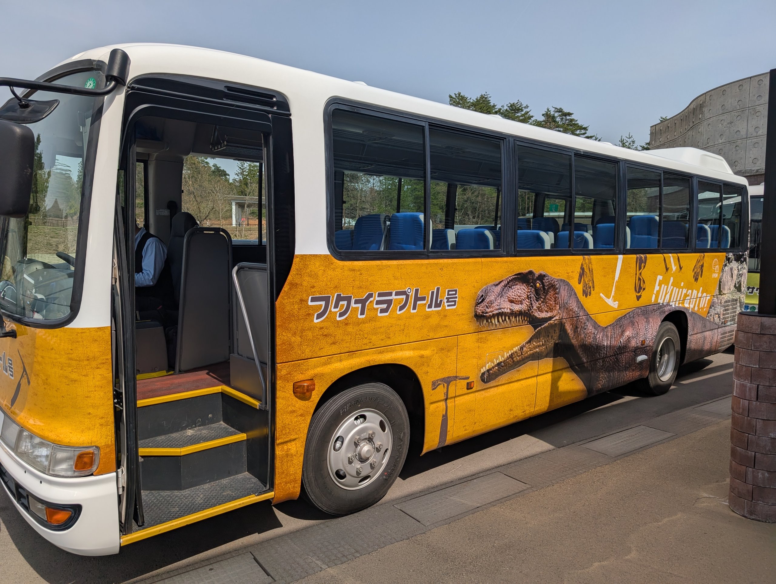 車体にフクイラプトルの絵が描かれた、黄色いバス
