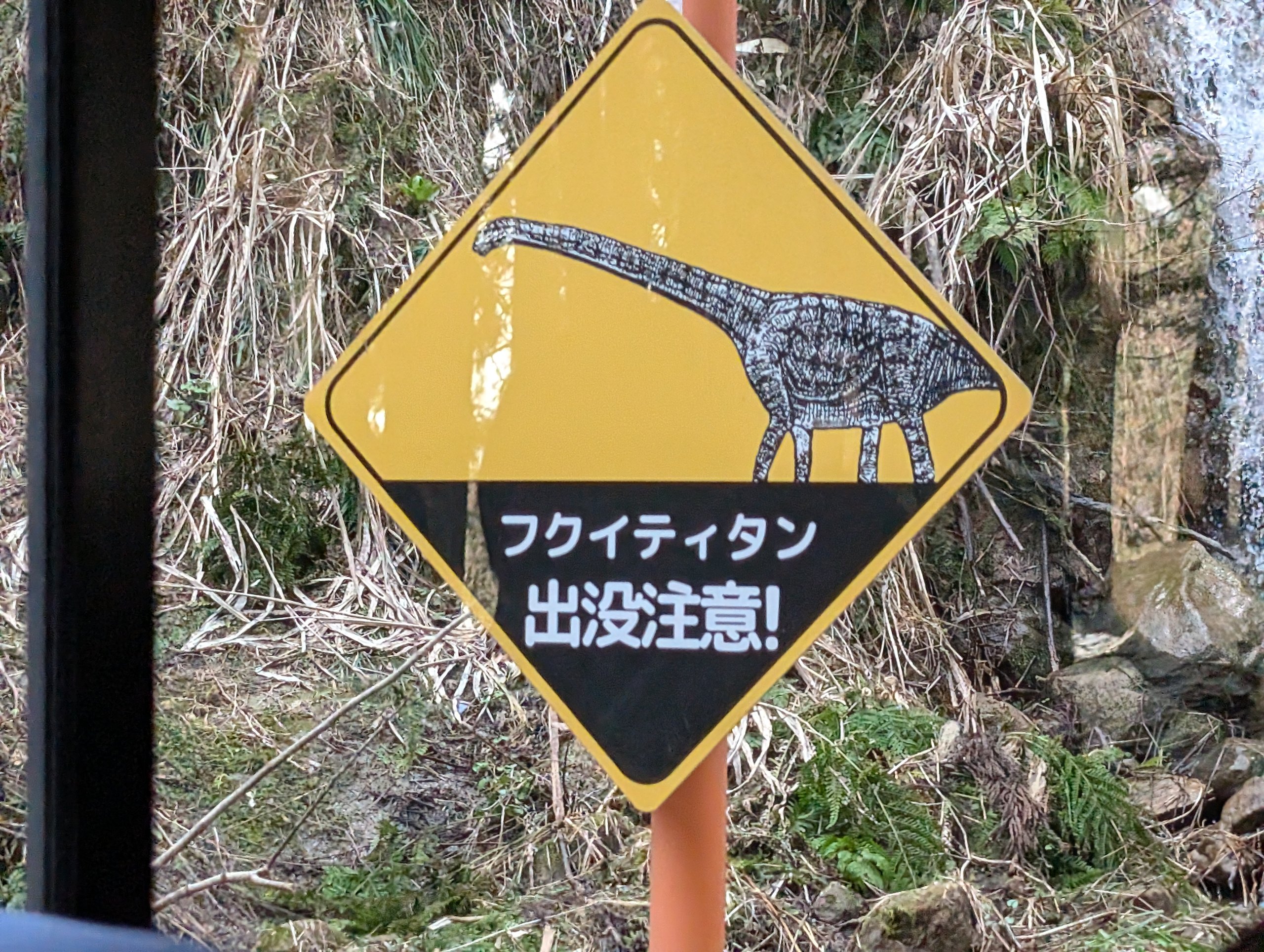 首の長い恐竜の絵と「フクイティタン出没注意!」の文字の看板