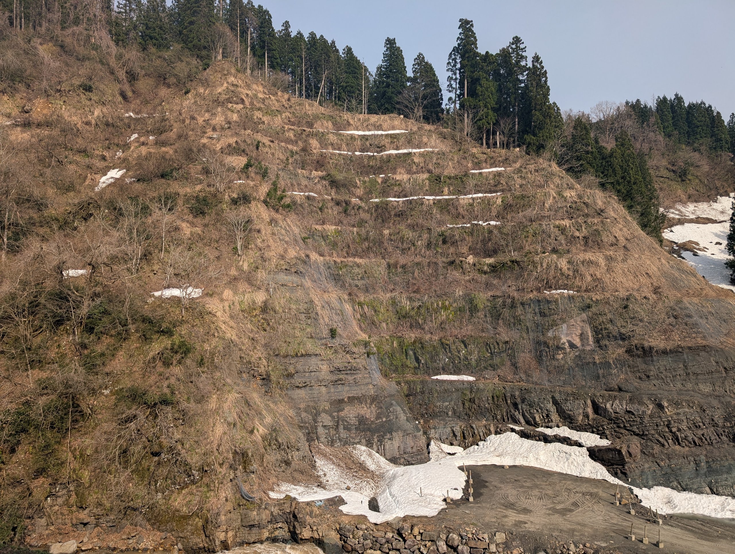 しま模様の地層が続く、山の斜面の崖