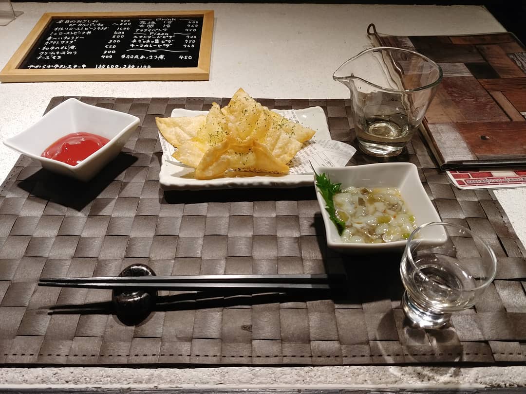 カウンターに並んだフライドポテトと小鉢、日本酒