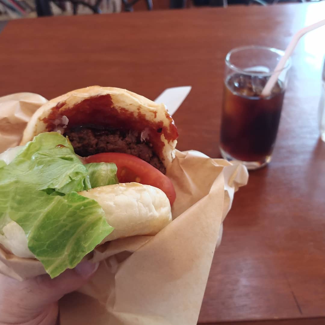 手に持ったハンバーガーとアイスコーヒー
