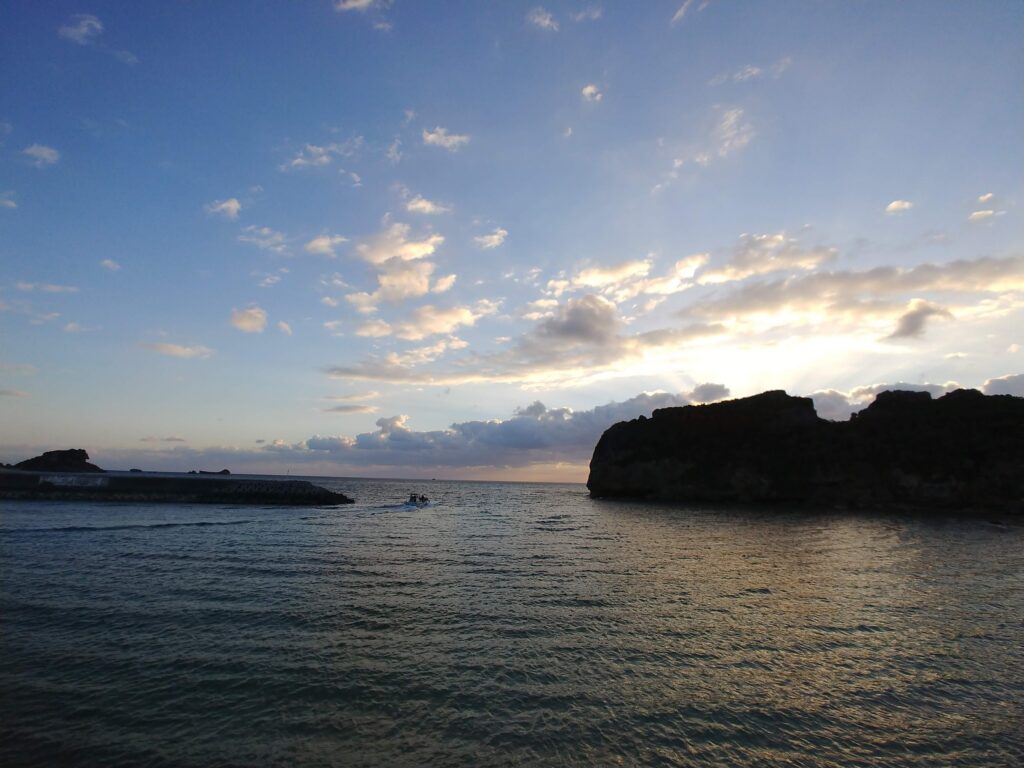 朝の浜比嘉島。雲間から光が差す海と岩の島