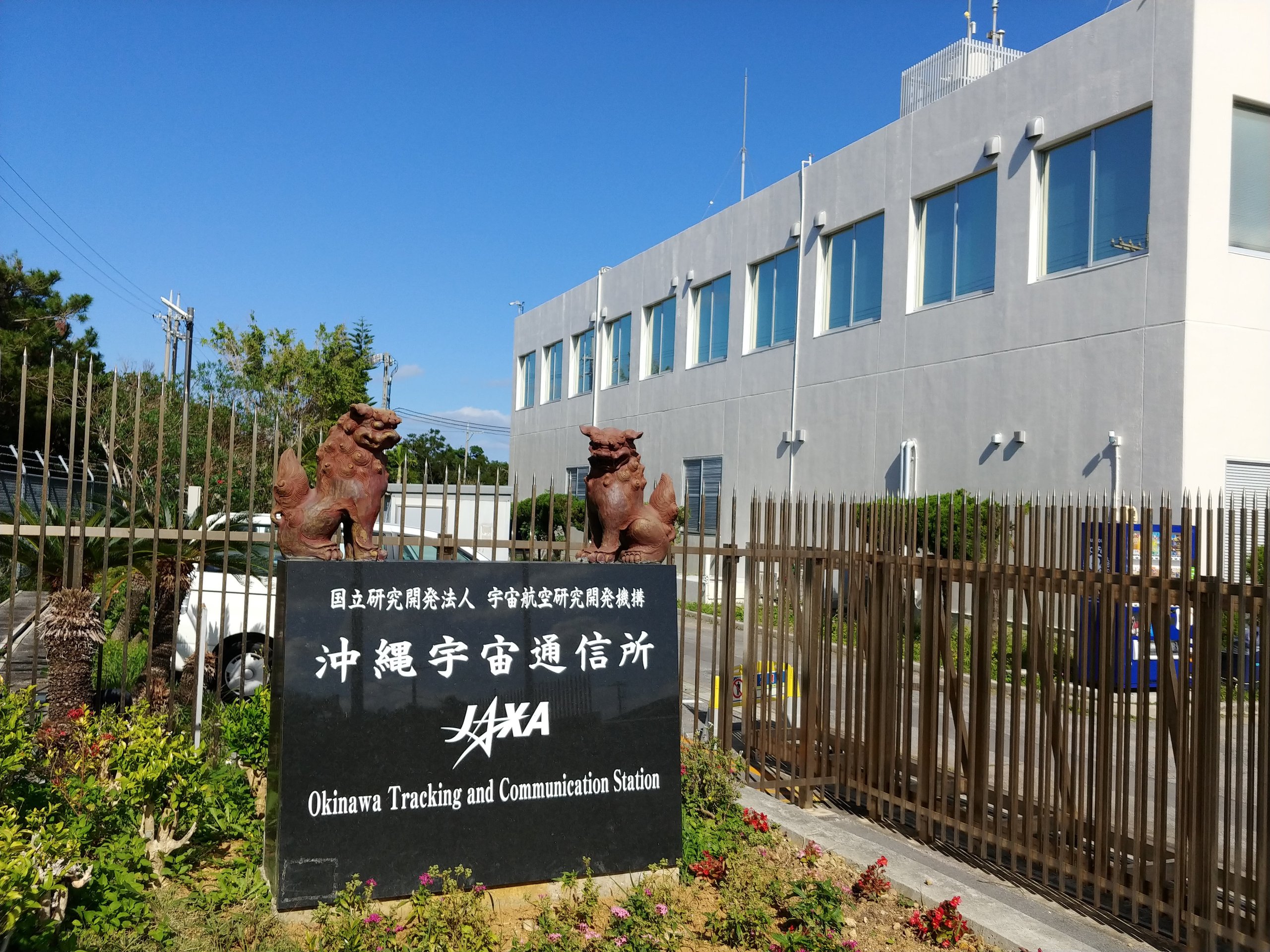 シーサーが乗ったJAXA沖縄宇宙通信所の看板と建物