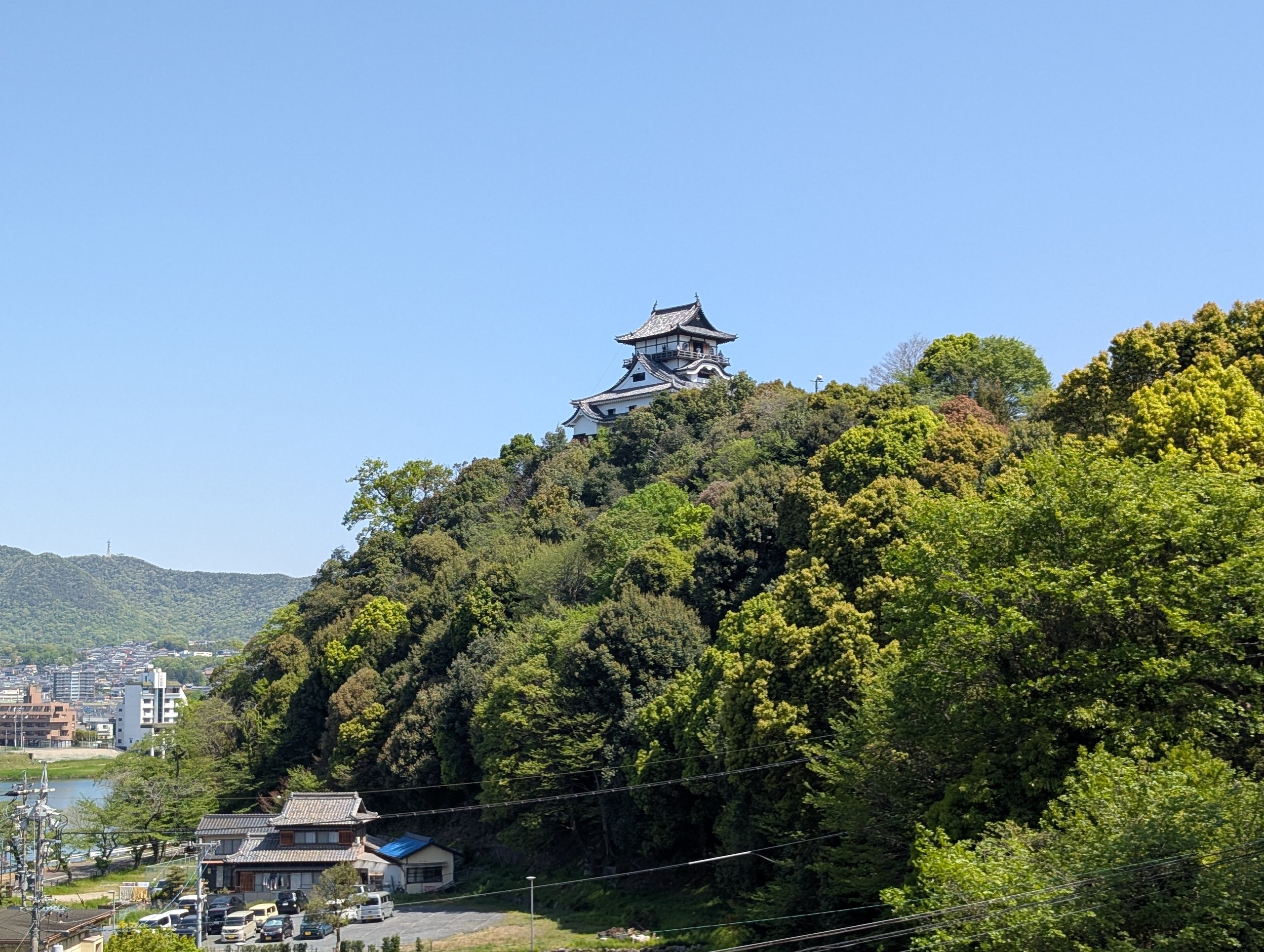 木々に覆われた山の上に立つ犬山城の天守と、ふもとの町