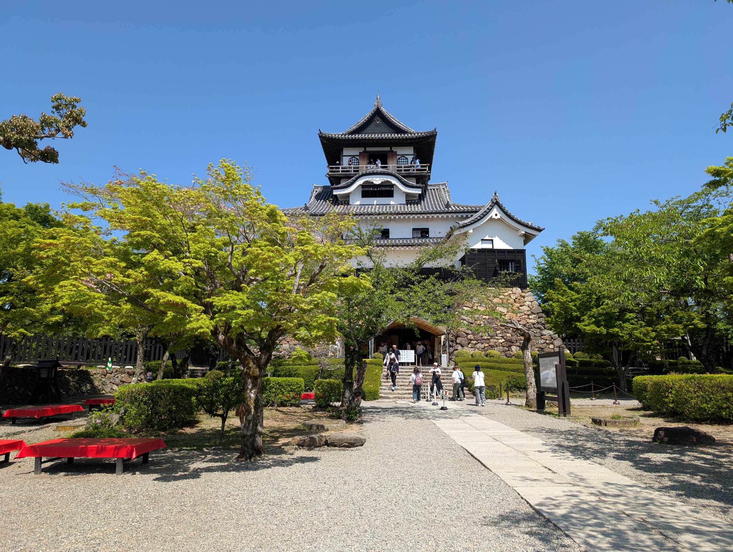 青空の下、木々の向こうに立つ犬山城の天守
