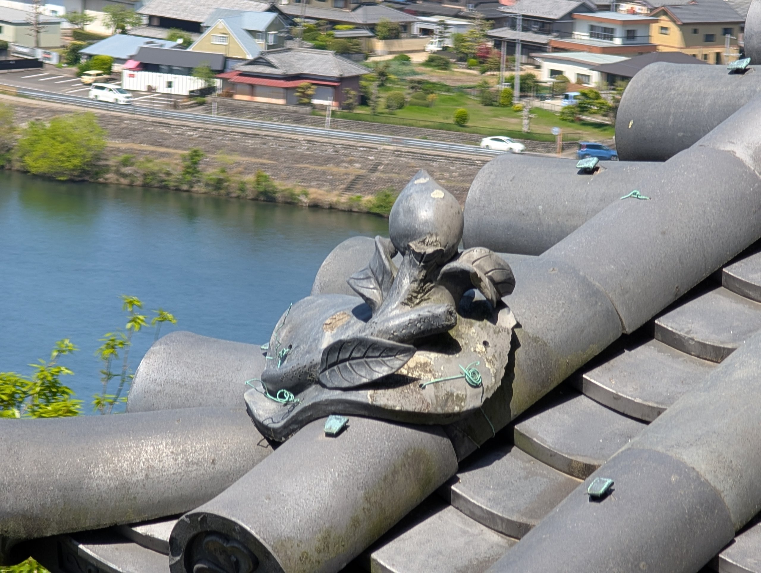 天守の屋根の飾り瓦と、その下に流れる川