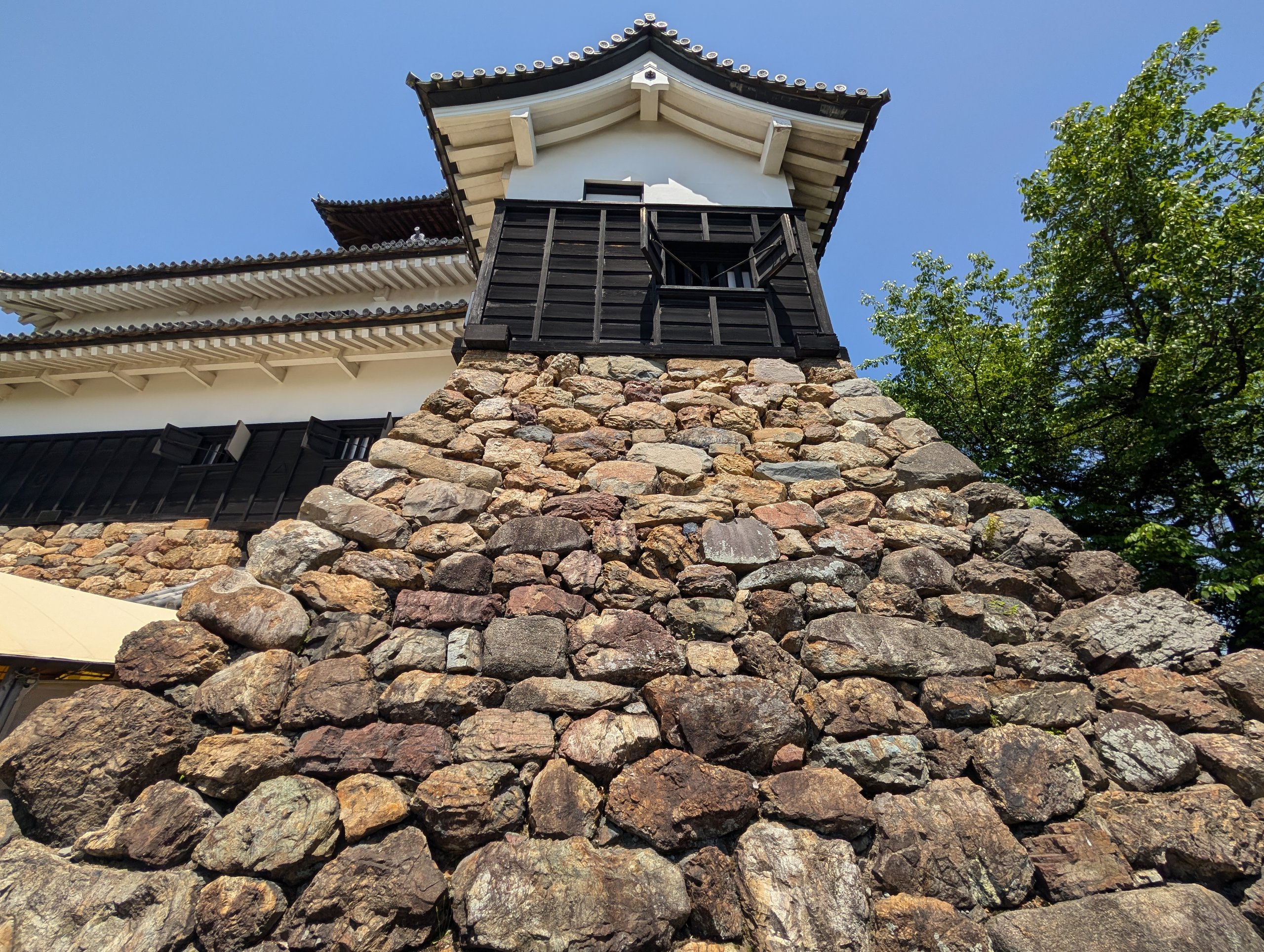 下から見上げた、石垣の上の天守の角