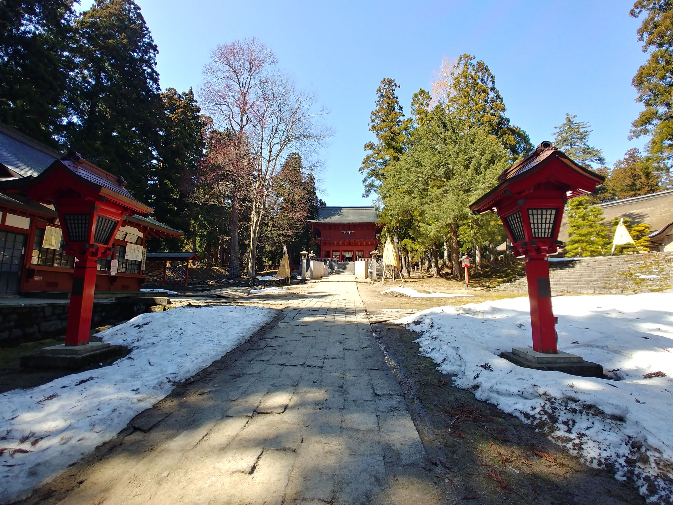 雪の残る石畳の参道と朱色の灯籠