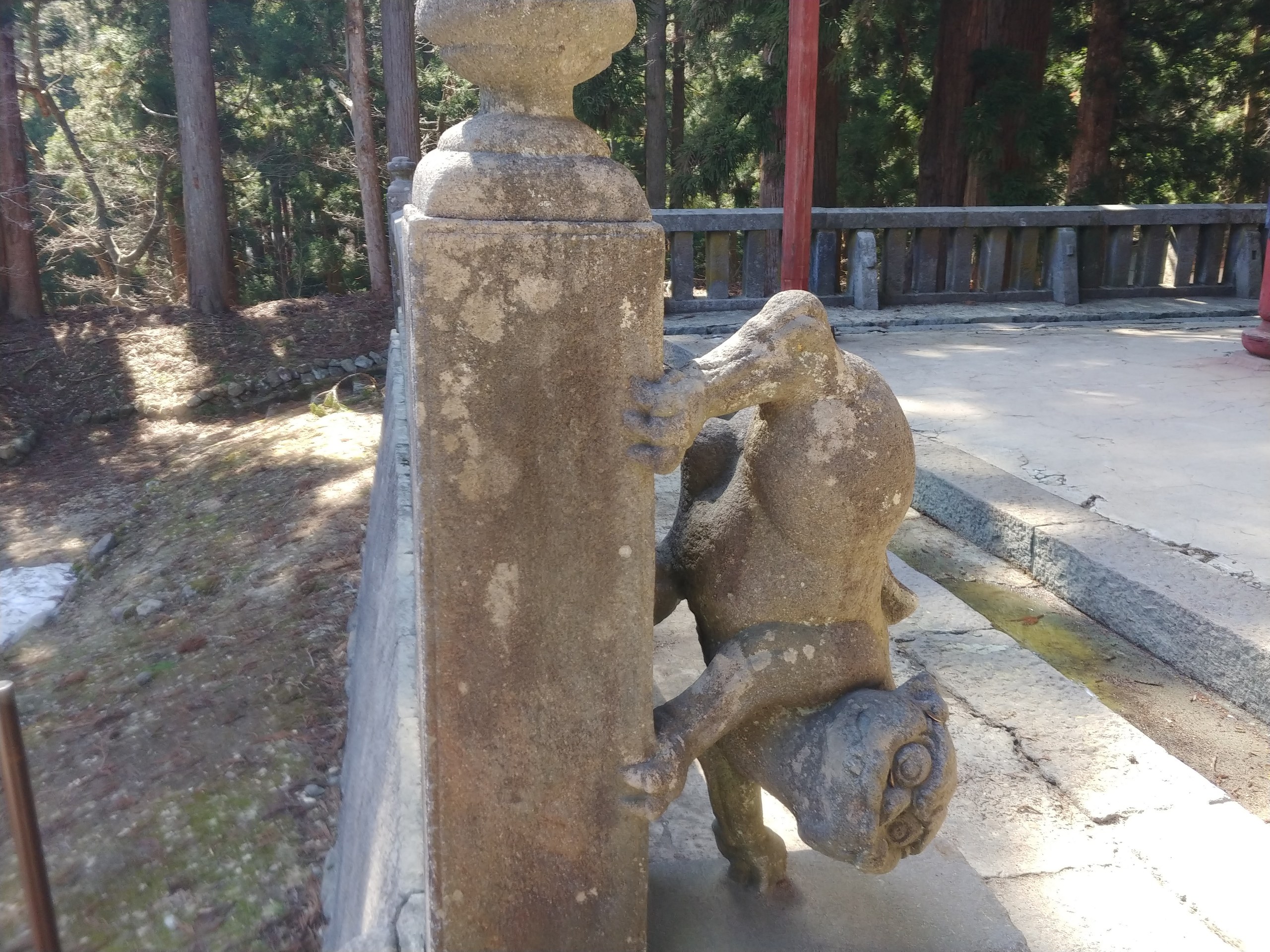 頭を下にして柱にしがみつく狛犬