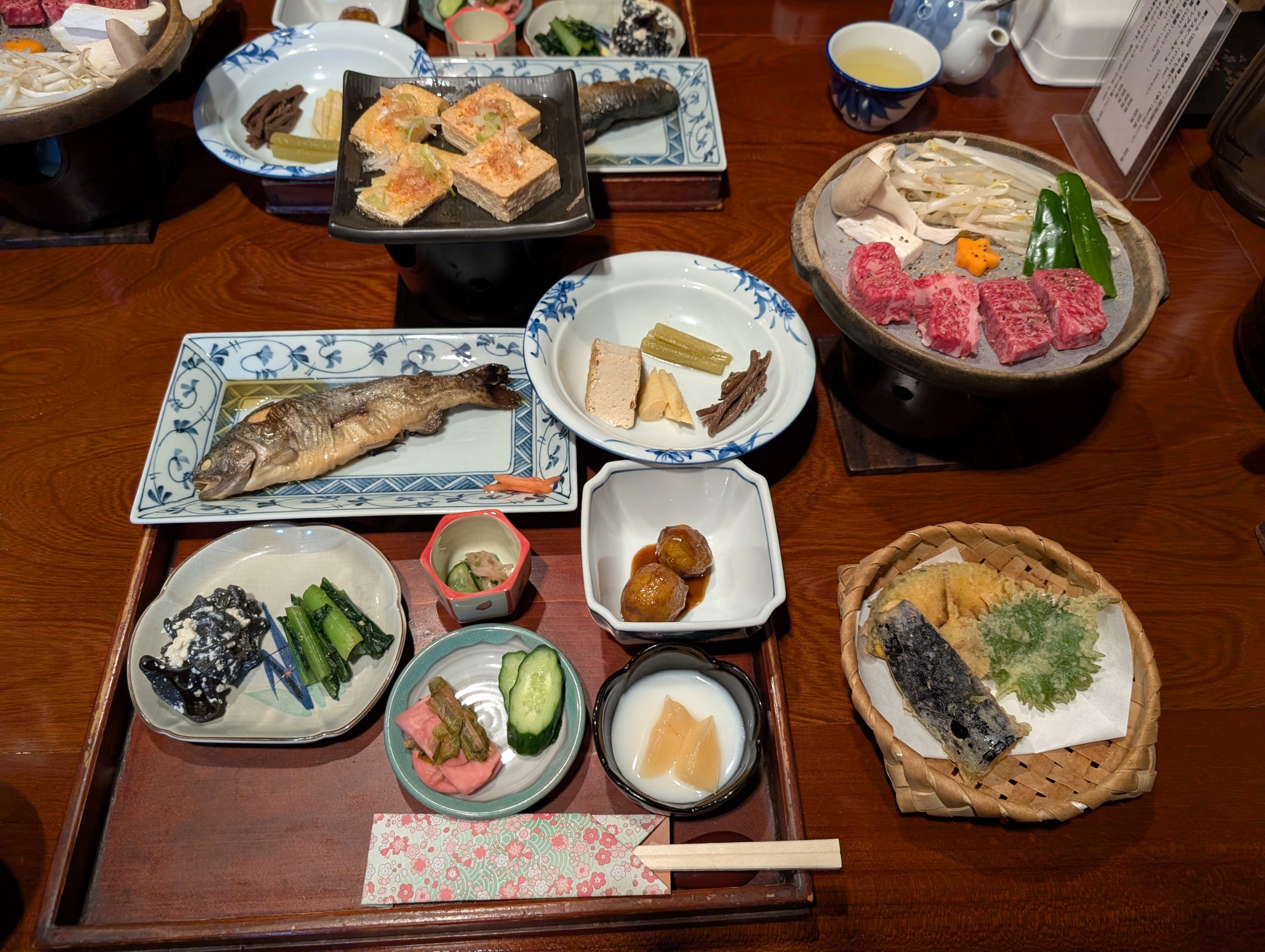 川魚や肉、小鉢が並ぶ夕食