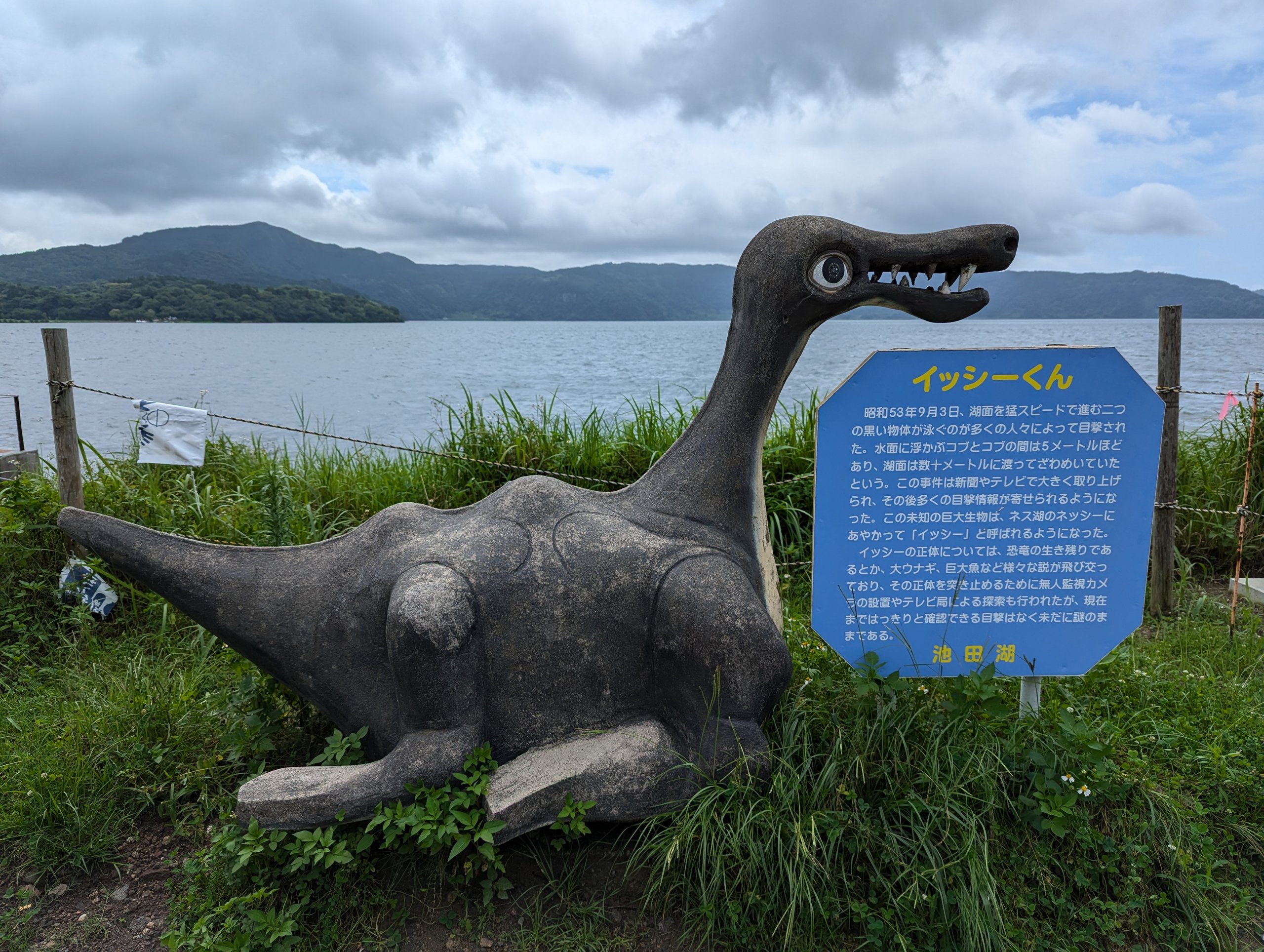 湖を背に立つ、恐竜のような「イッシーくん」の像