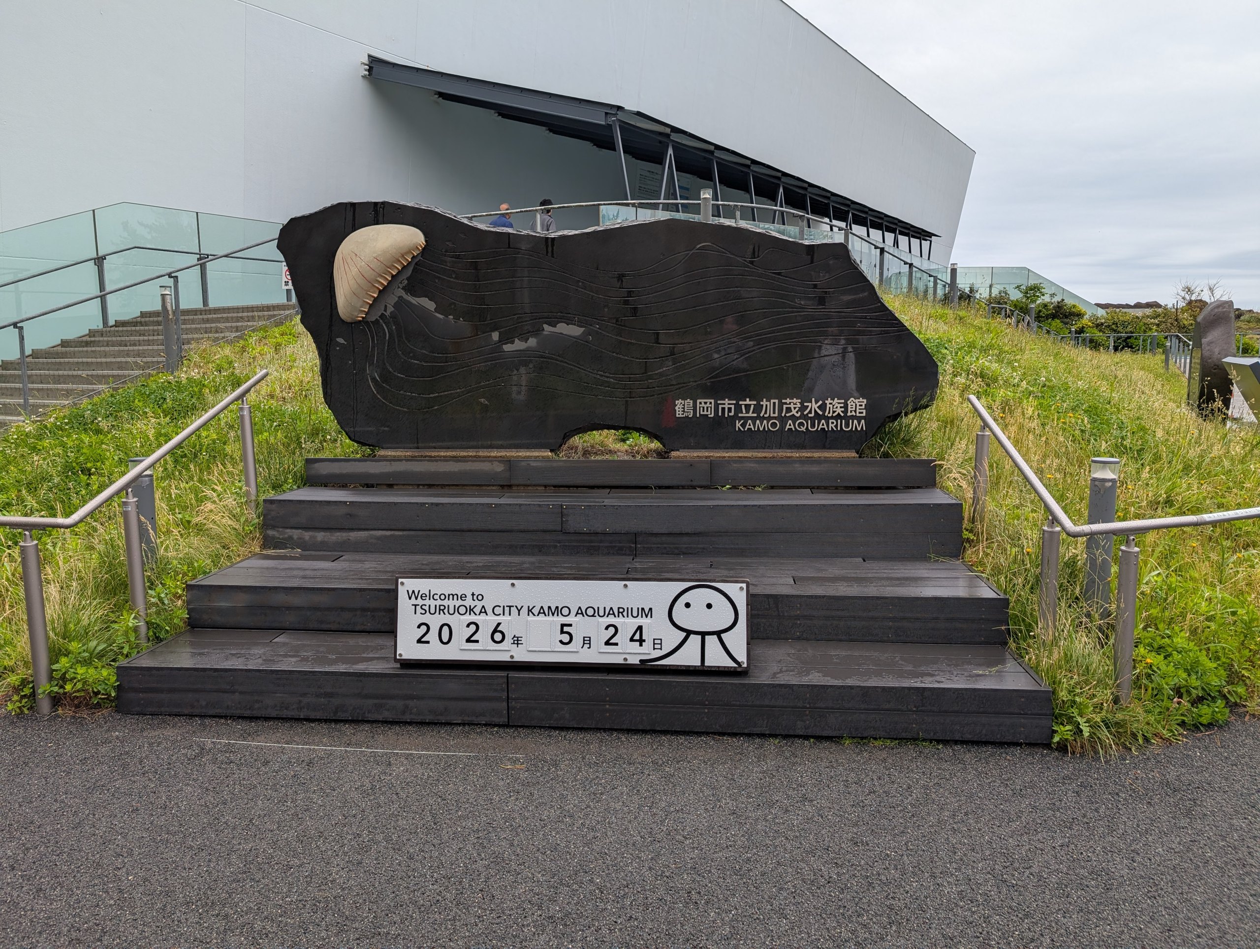 「2026年5月24日」の札が置かれた、加茂水族館の入口の石碑