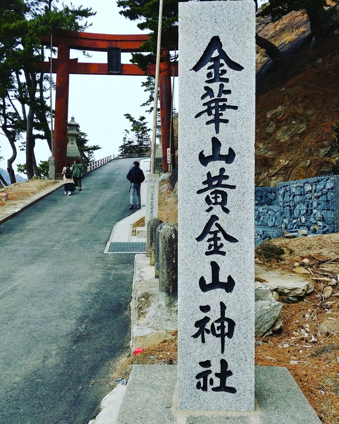 「金華山黄金山神社」の石柱と赤い鳥居の参道