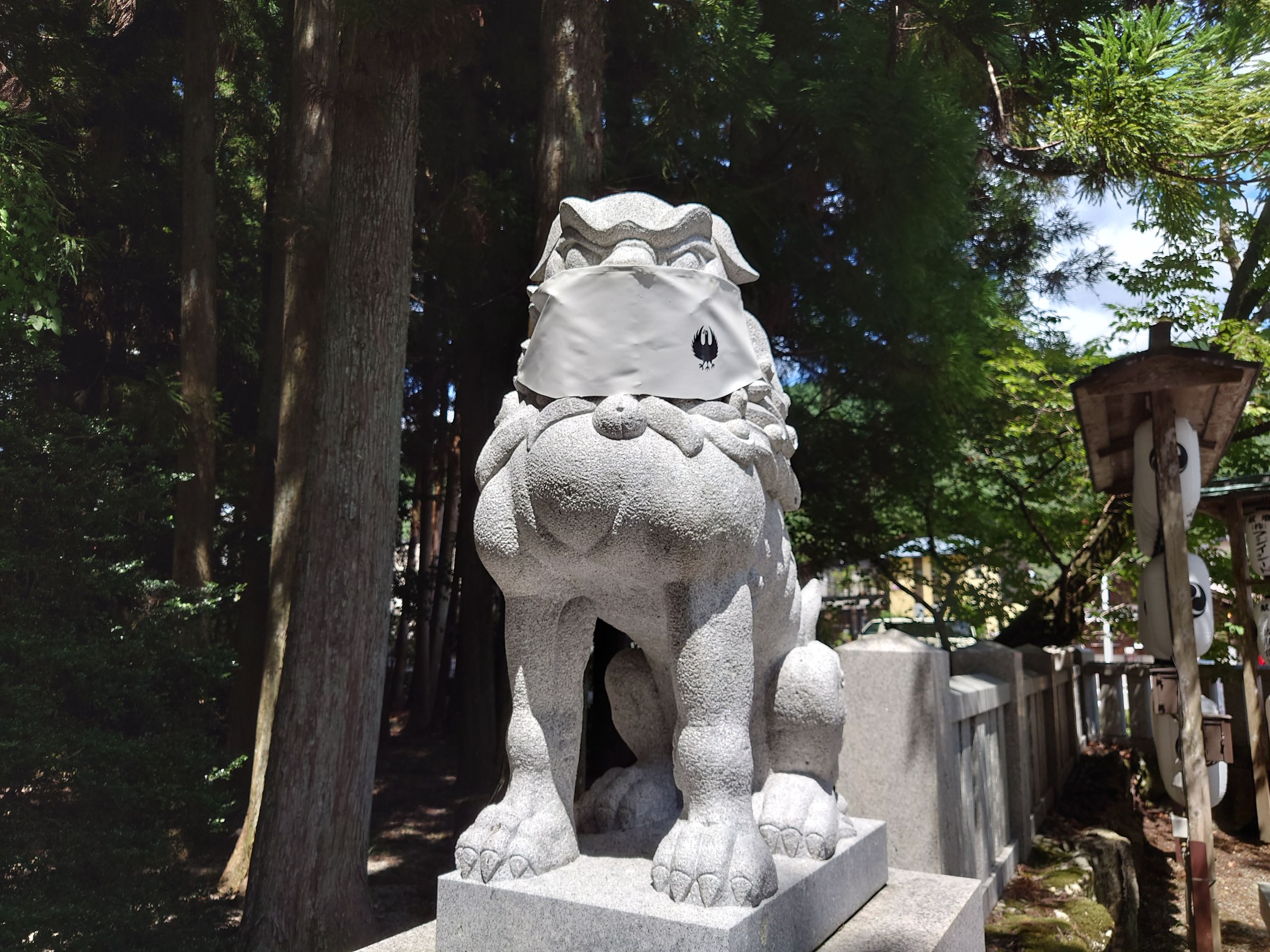 杉木立の中に立つ、白い狛犬