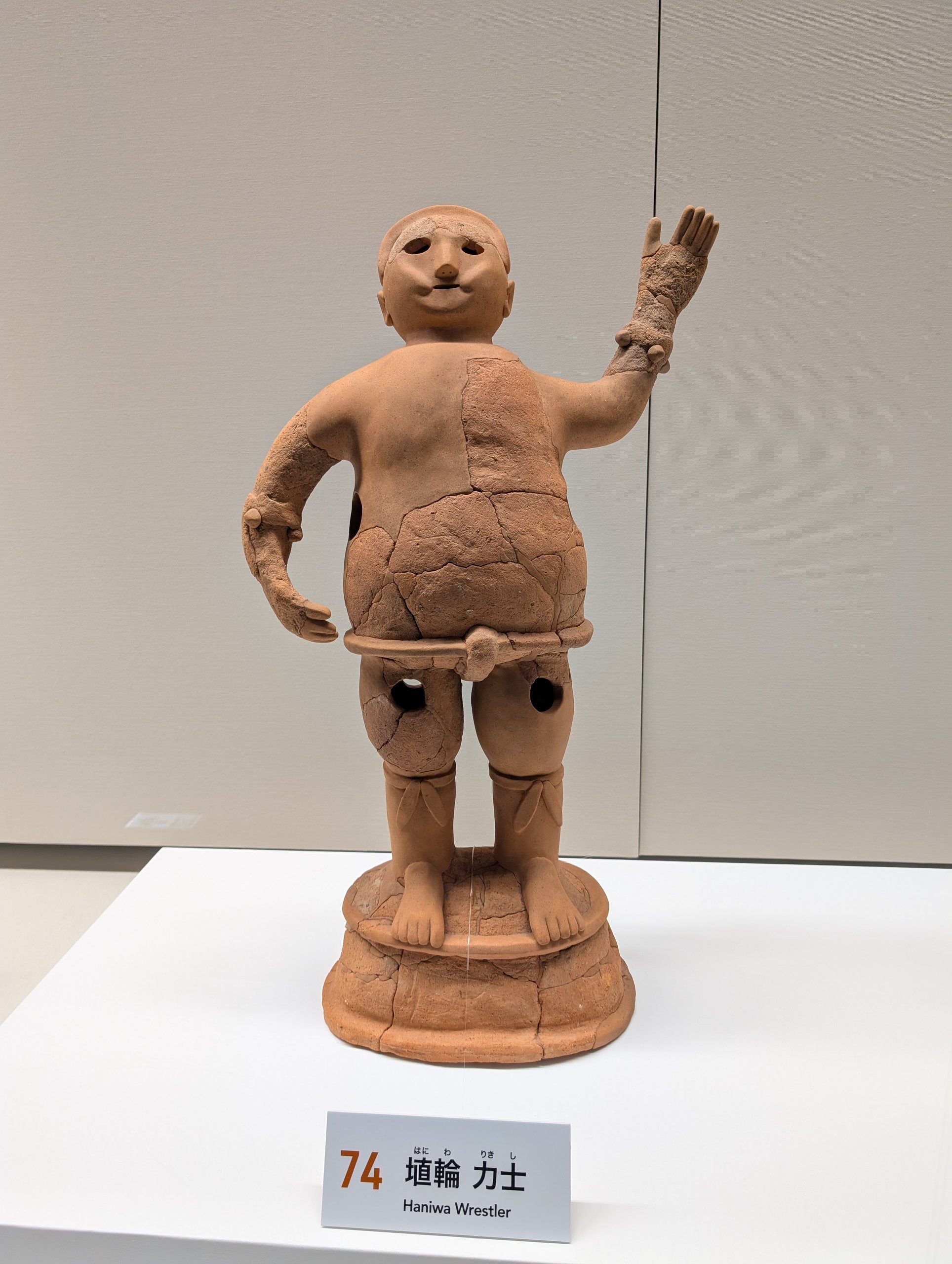 片手を上げた力士のはにわと、「埴輪 力士」の札