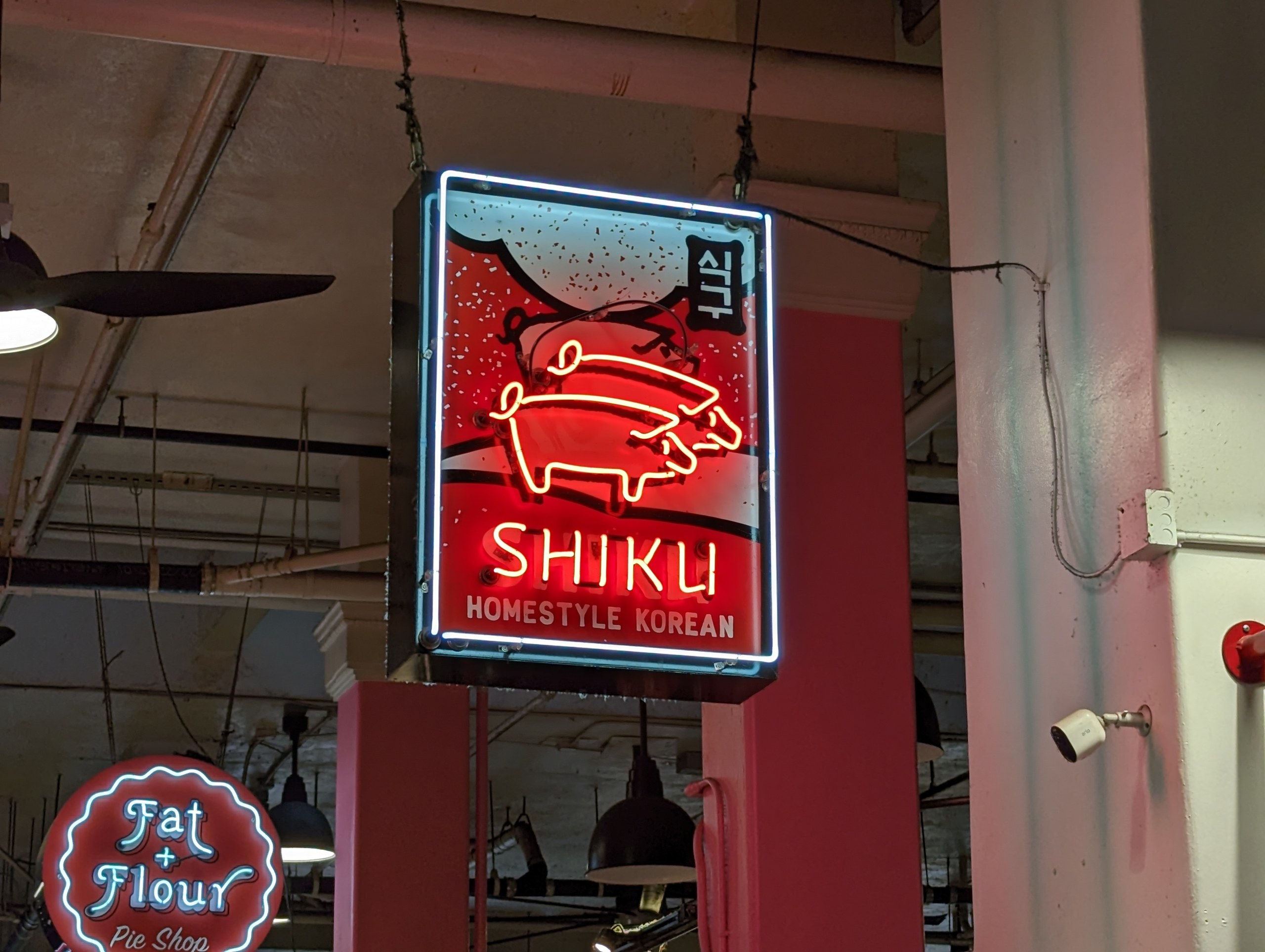 「SHIKU」の文字が光る、マーケットの韓国料理店のネオン看板