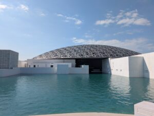 水の向こうに建つ白い建物と、その上をおおう網目模様のドーム