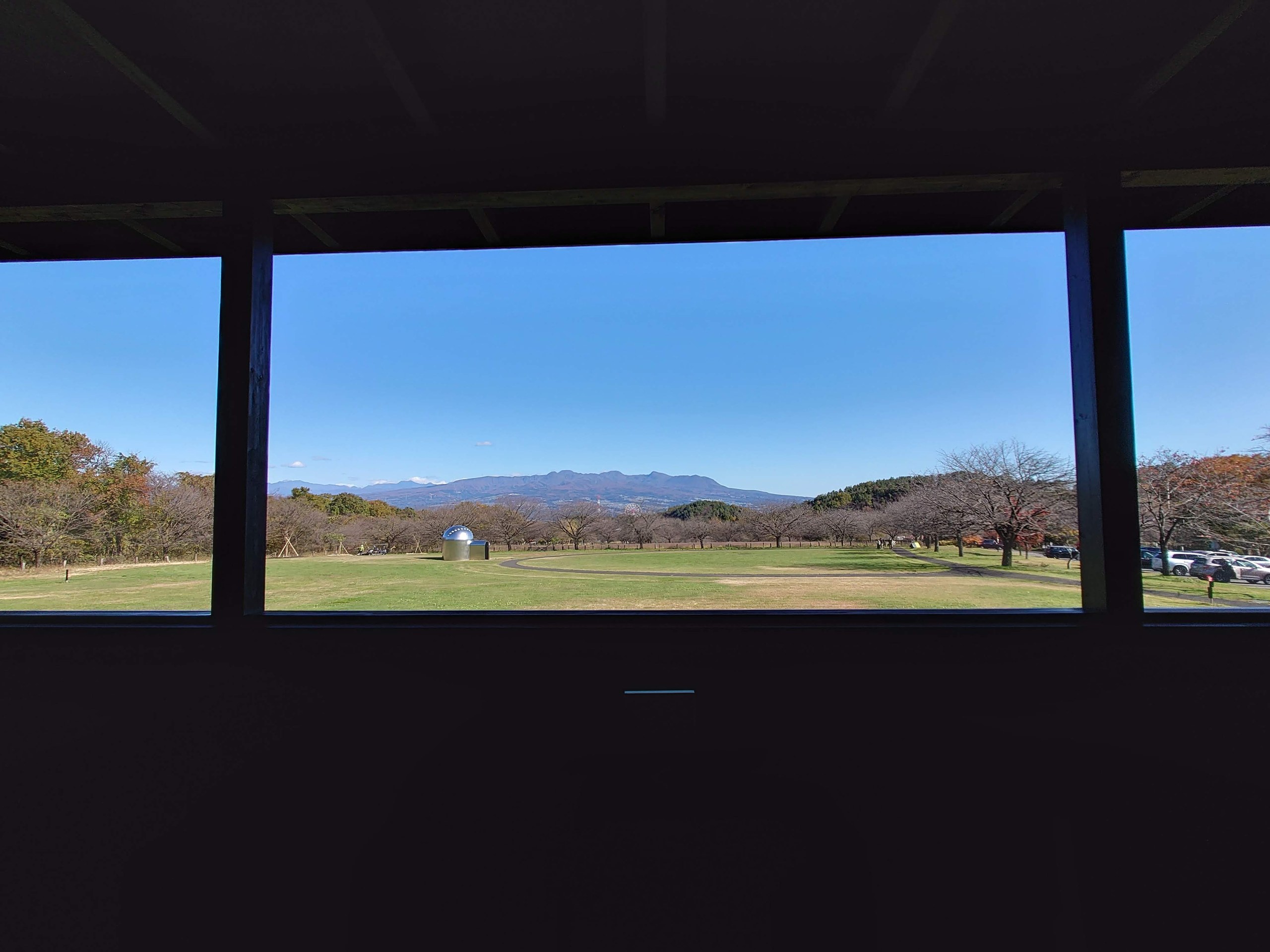 ガラス越しに見える芝生と遠くの山並み