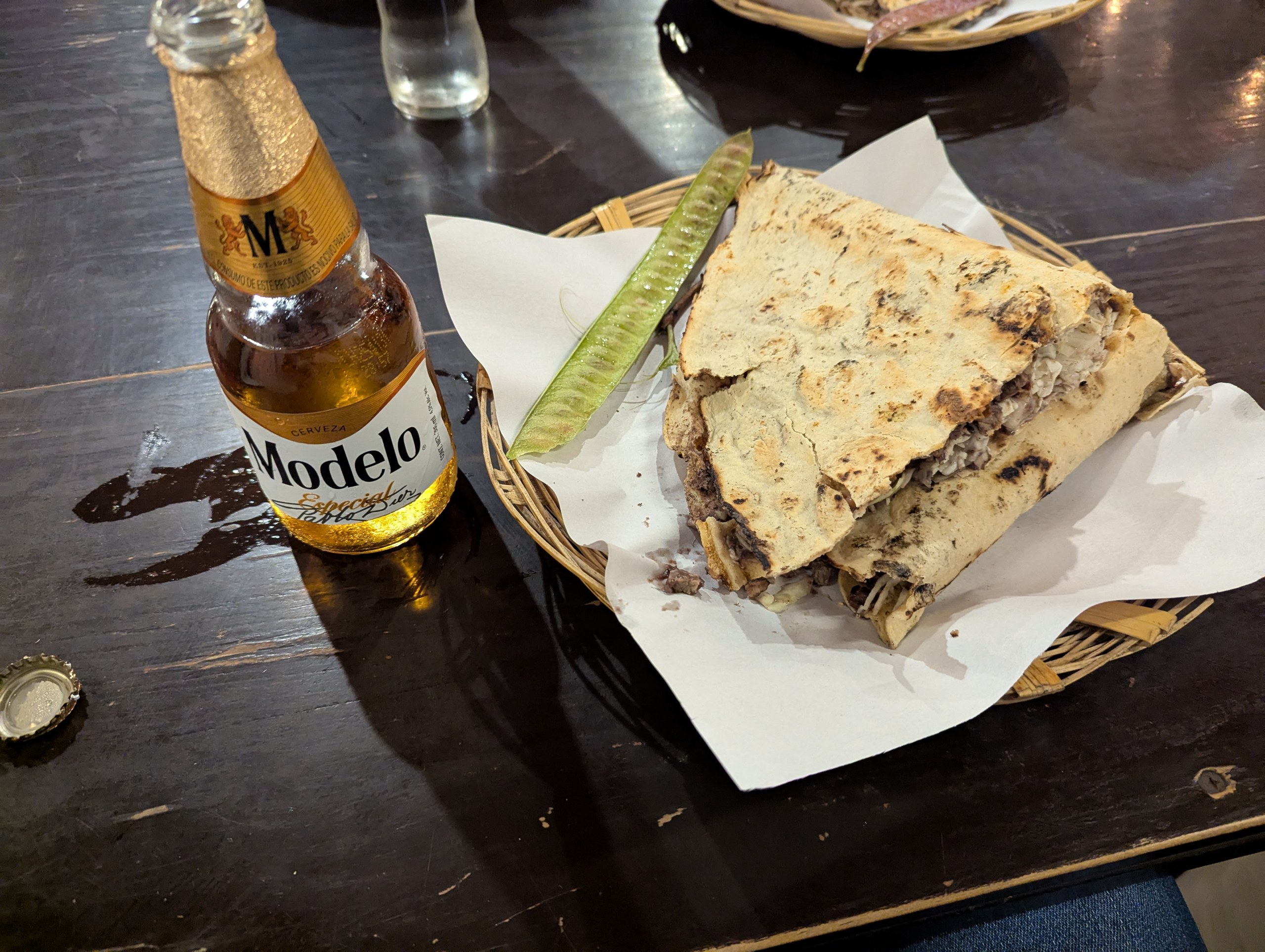 かごに盛られたトルティーヤの料理と、モデロのビール瓶