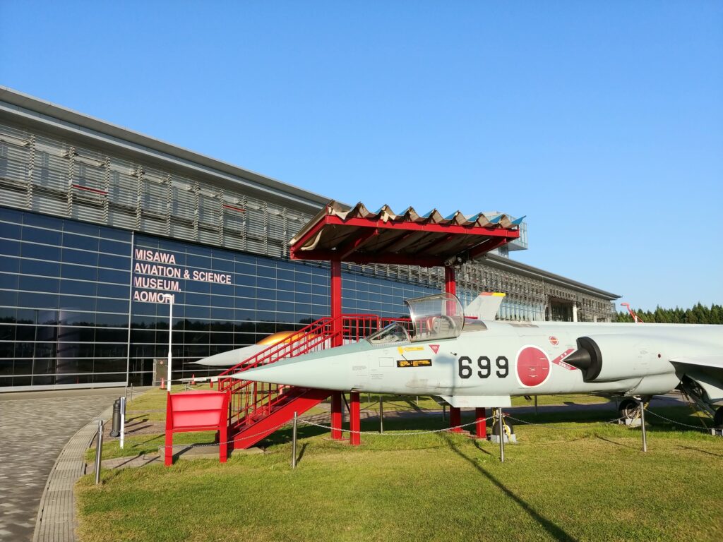 青森県立三沢航空科学館の建物と、前に展示された自衛隊の戦闘機