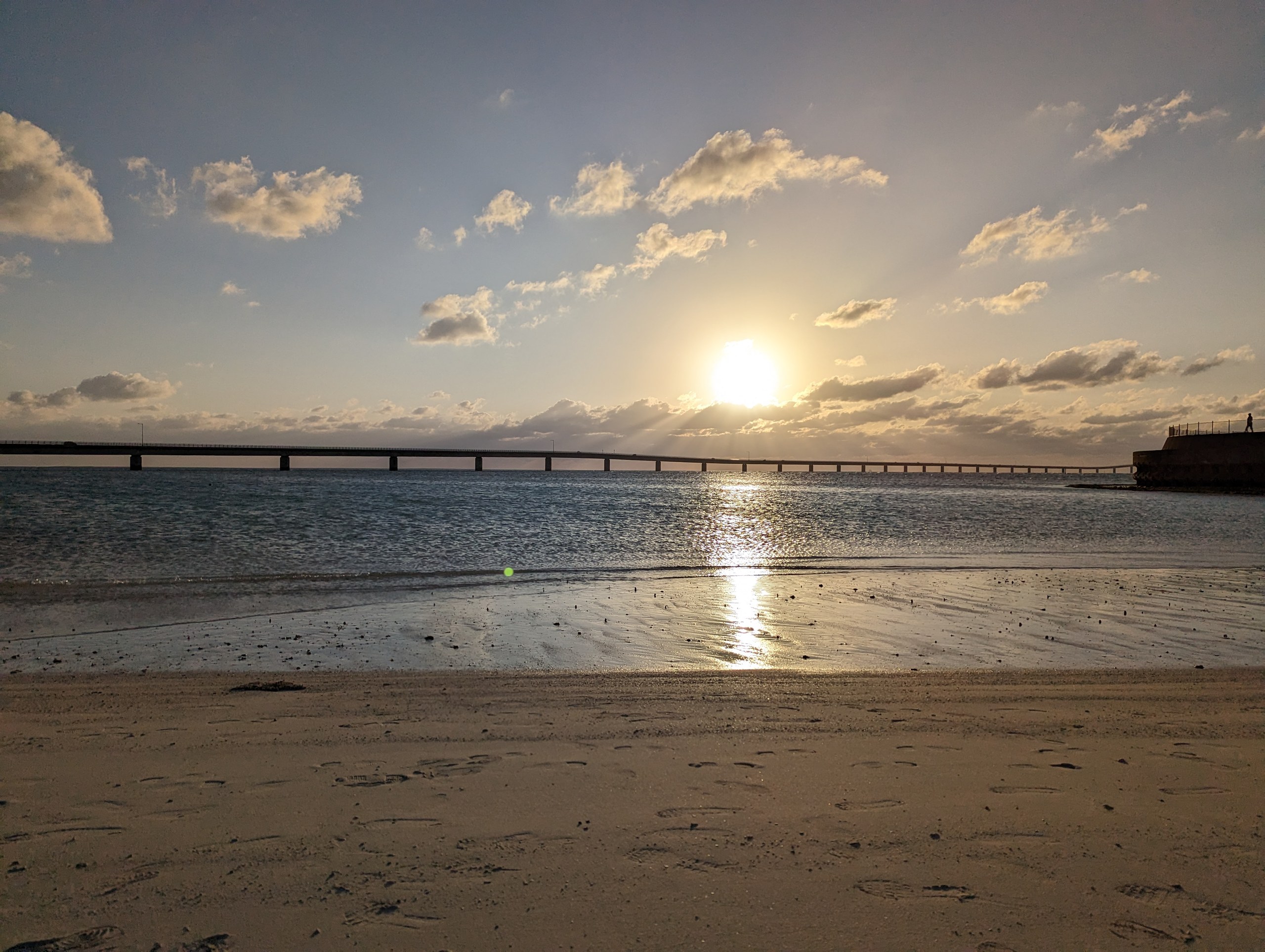 伊良部大橋の向こうに沈む夕日と、浜に映る光