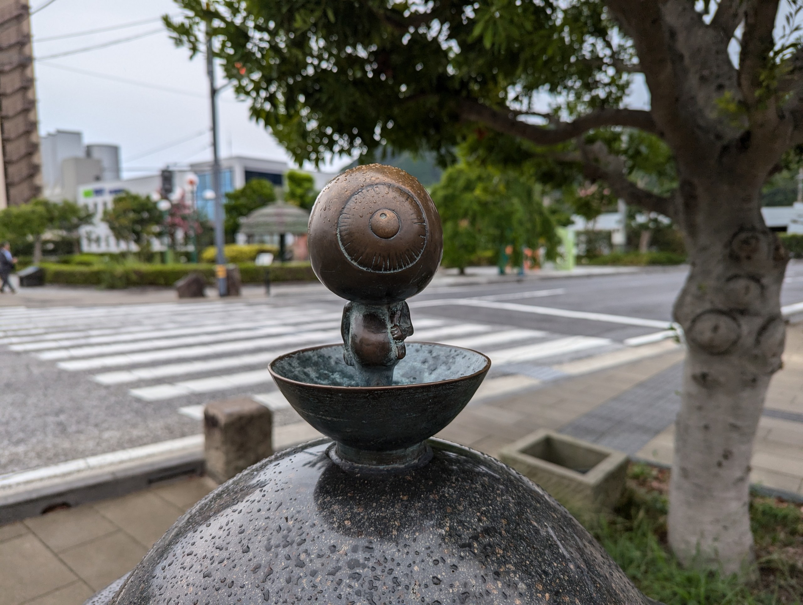 お椀の上に立つ目玉おやじのブロンズ像と、朝の水木しげるロードの横断歩道