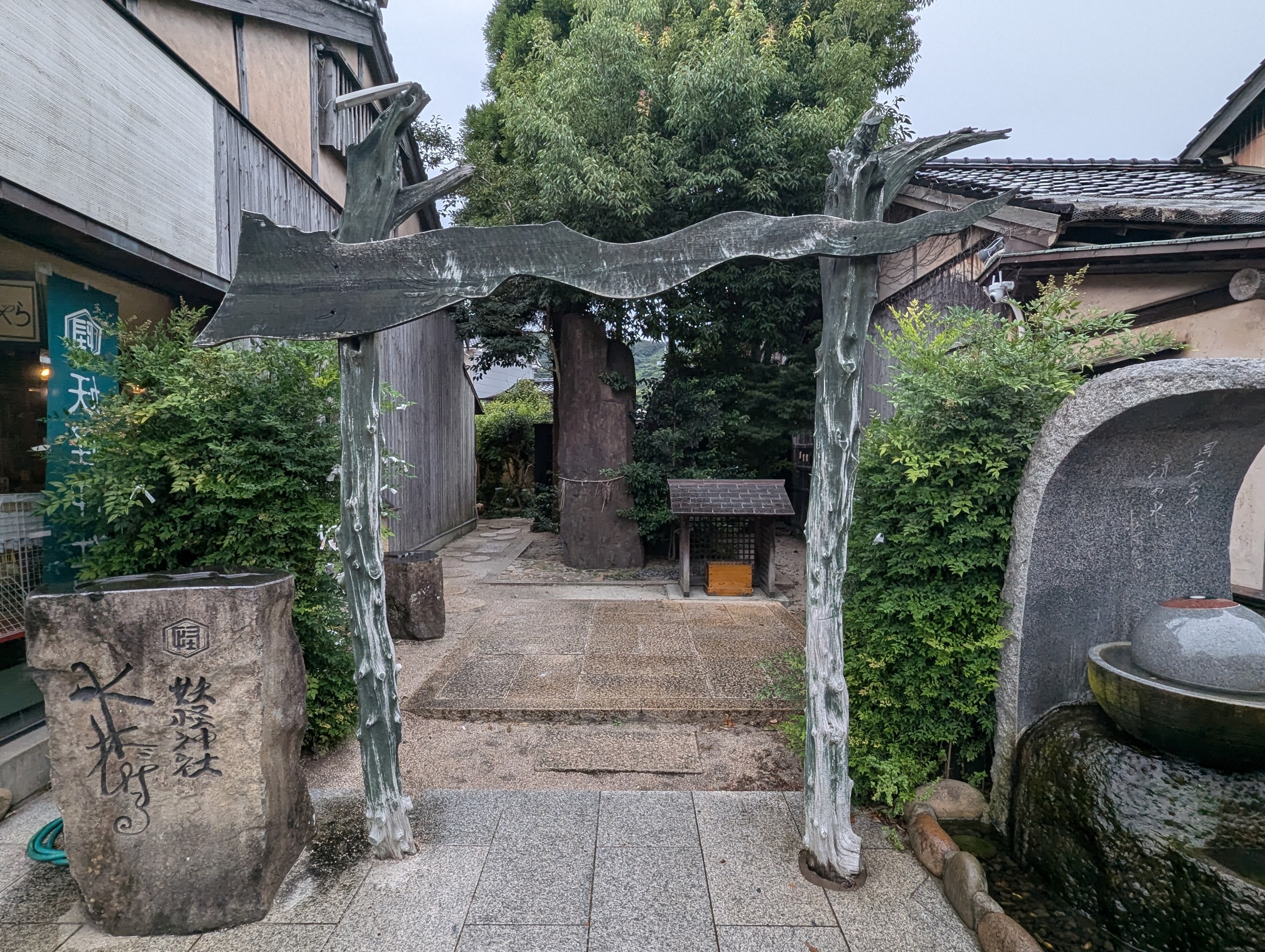 「妖怪神社」と刻まれた石と、木の枝のような形をした鳥居。奥に大きな石と小さな社
