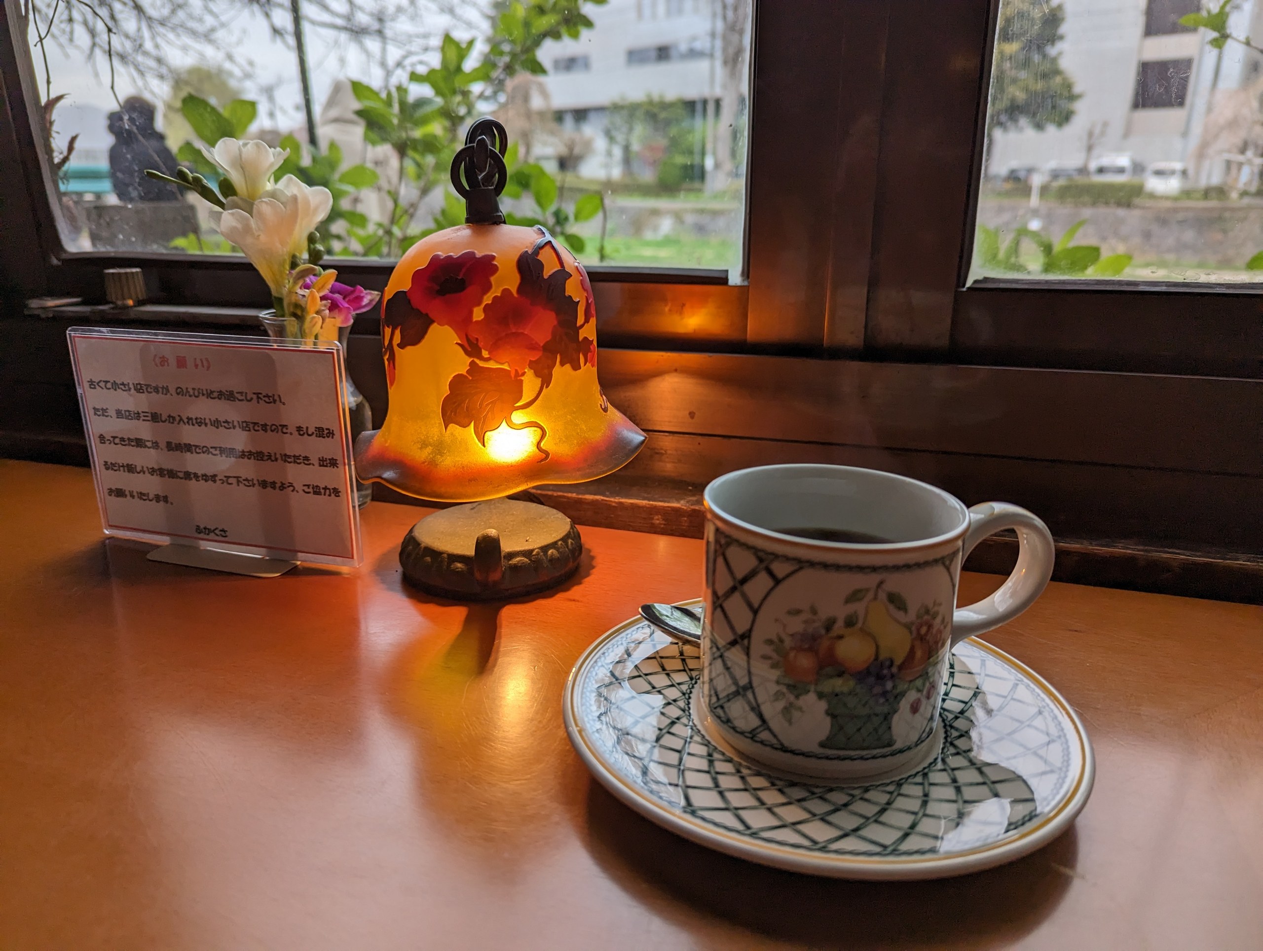 ランプの明かりのそばに置かれた、花柄のコーヒーカップ