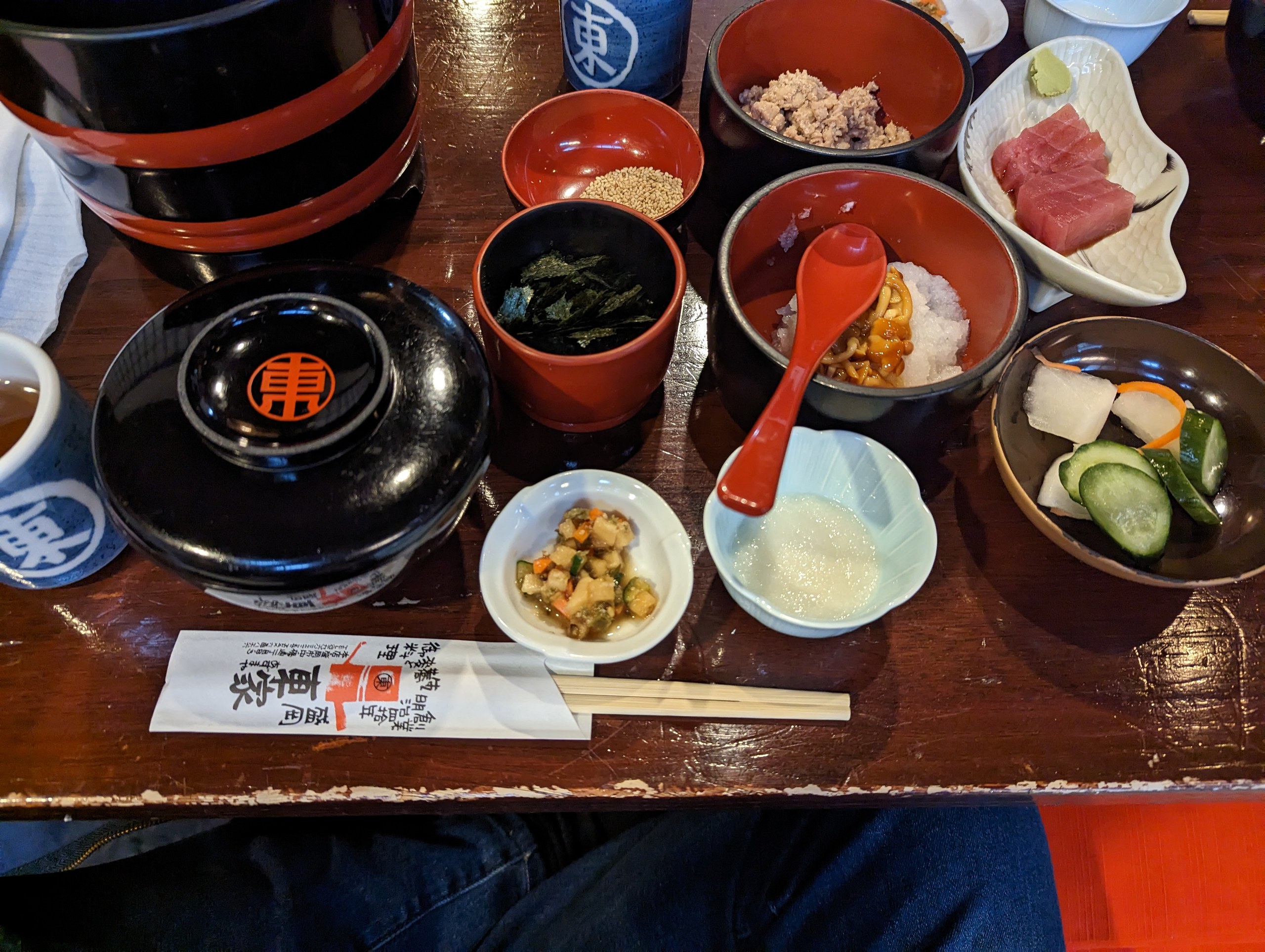 漆塗りのお椀と、薬味や刺身の小皿が並ぶわんこそばの席