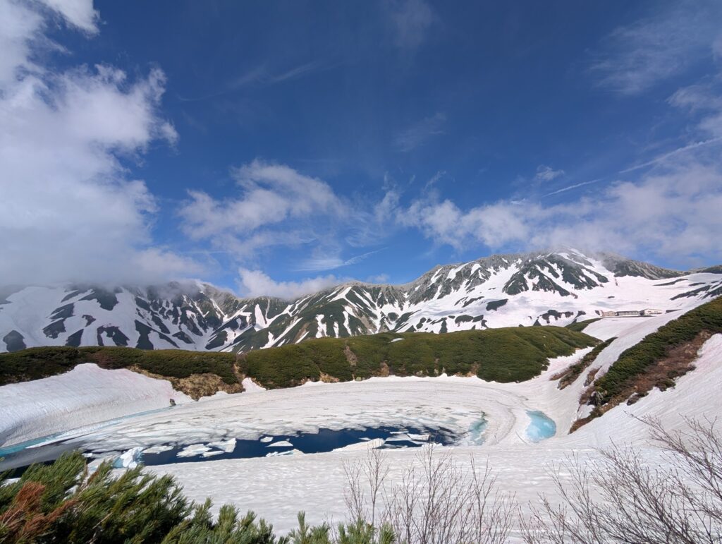 青空の下、雪の山と氷の浮かぶみくりが池