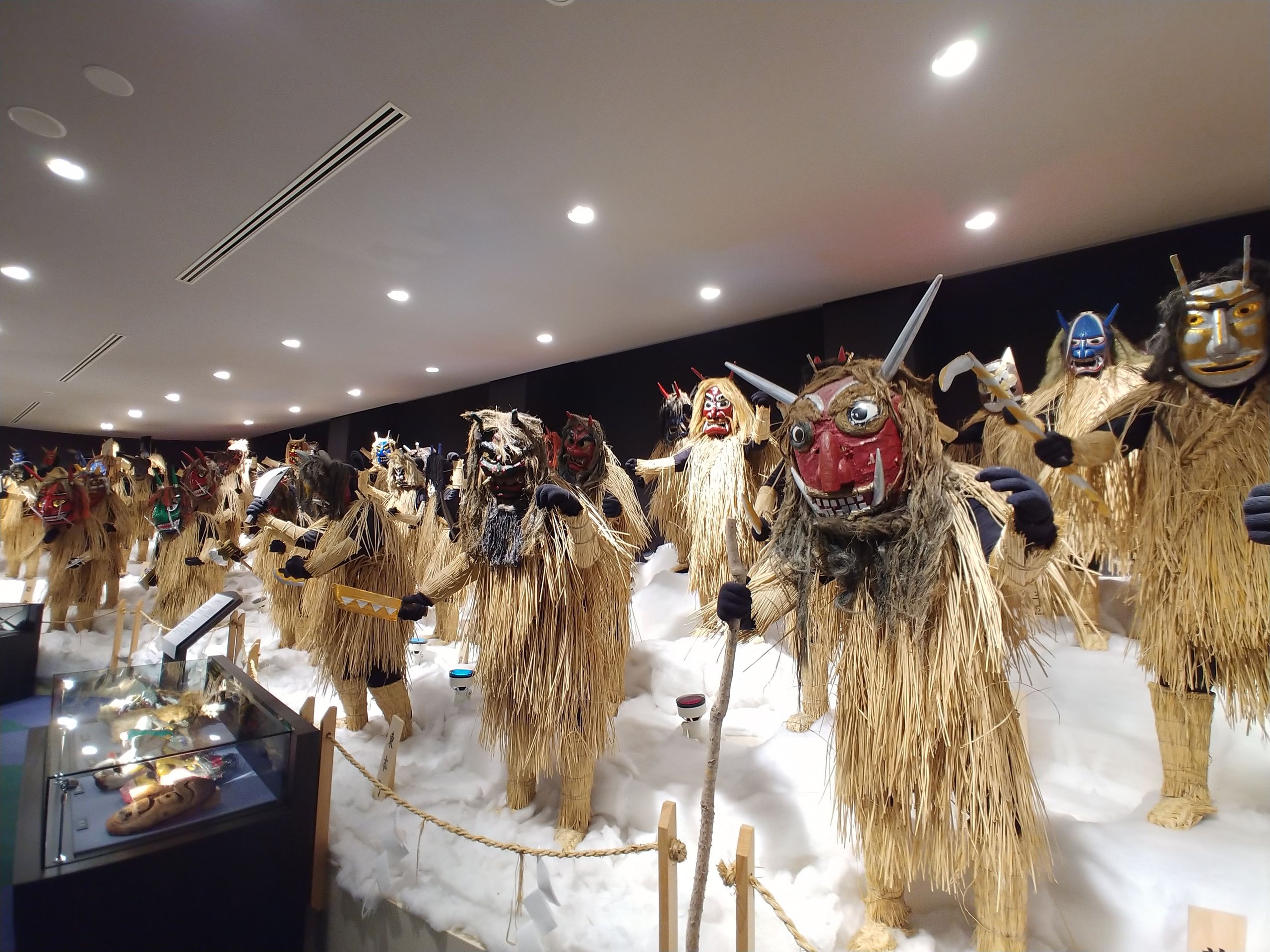 赤や青、金色の面をつけたなまはげが並ぶ展示