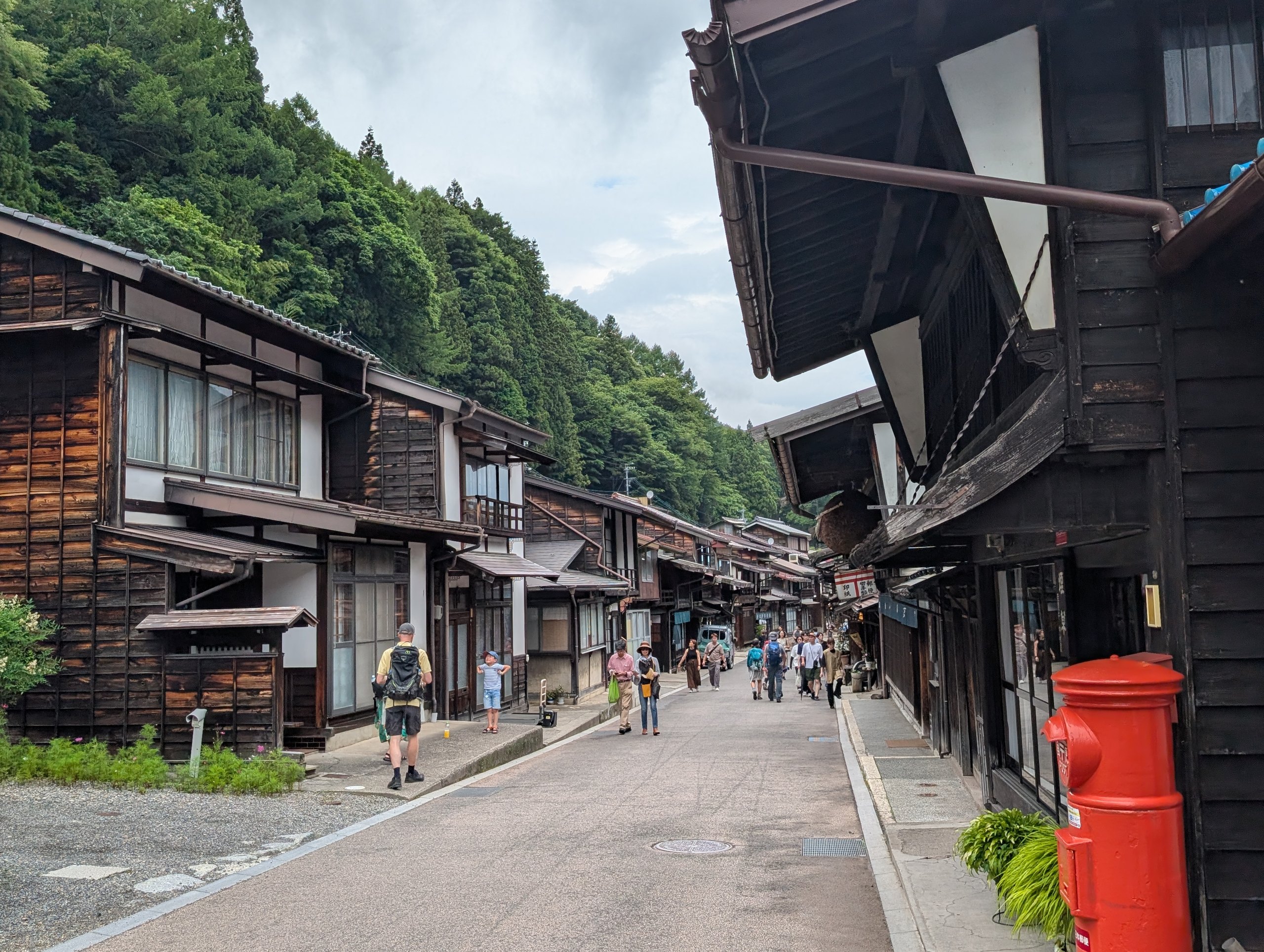 木造の家並みと、赤い丸ポストがある通り