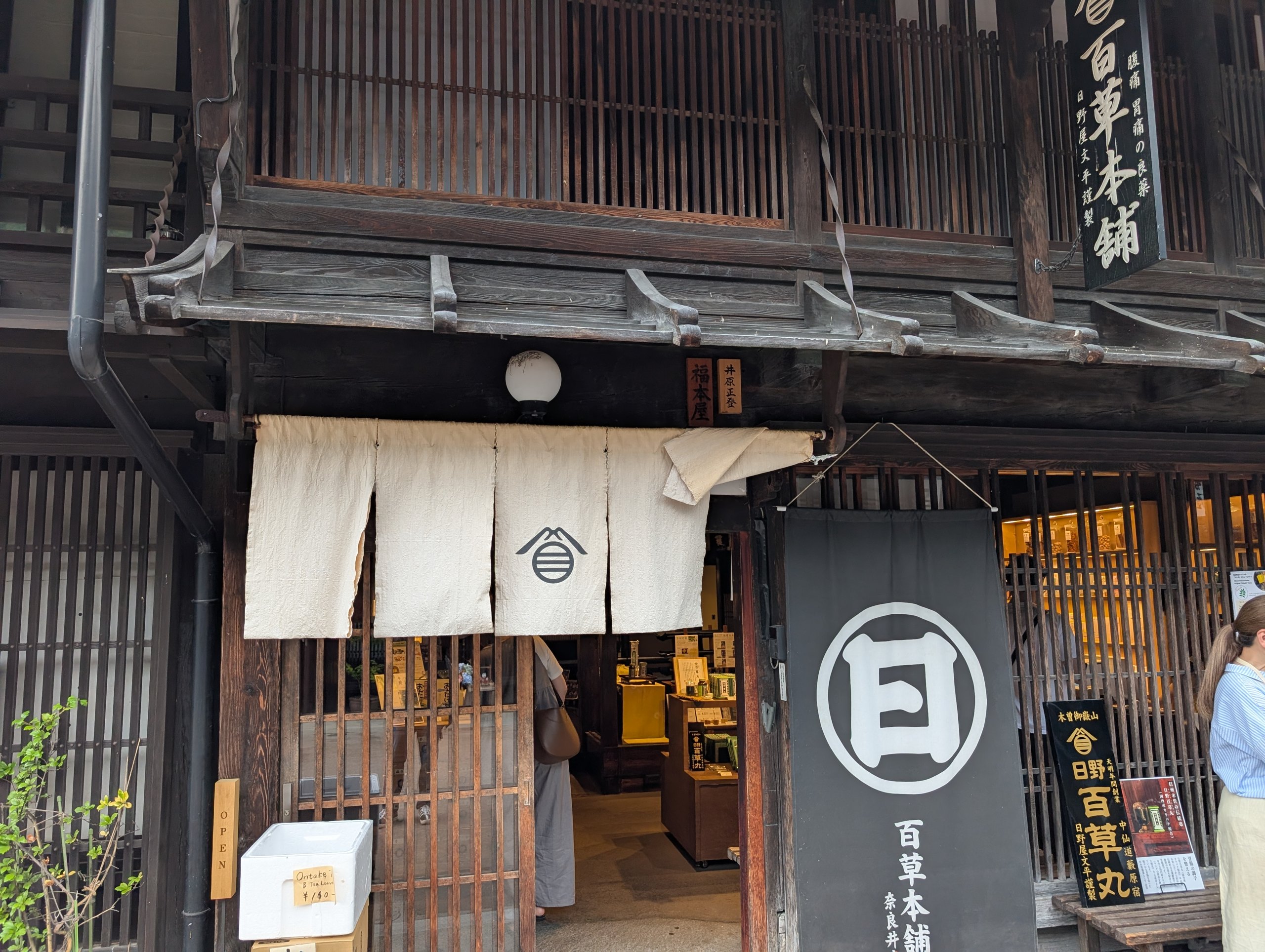 白い暖簾と「百草本舗」の看板がある、日野百草本舗 奈良井店